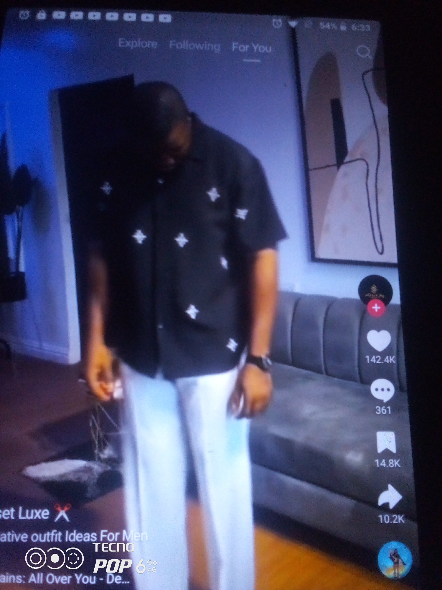 The image shows a person standing in front of a grey couch. The person is wearing a black shirt with white patterns and white pants. The person is looking down. On the right side of the image, there are social media icons, including a heart icon with the number 142.4K next to it. There is also a speech bubble icon with the number 361, a bookmark icon with the number 14.8K, and an arrow icon with the number 10.2K. At the bottom of the image, there is text that reads "set Luxe", "creative outfit Ideas For Men", "TECNO", "POP 6", and "Go 4G". The image is a screenshot from a mobile device, as indicated by the battery percentage, time, and navigation bar at the top. The location of Howayi, Nigeria is not discernible from the image.
