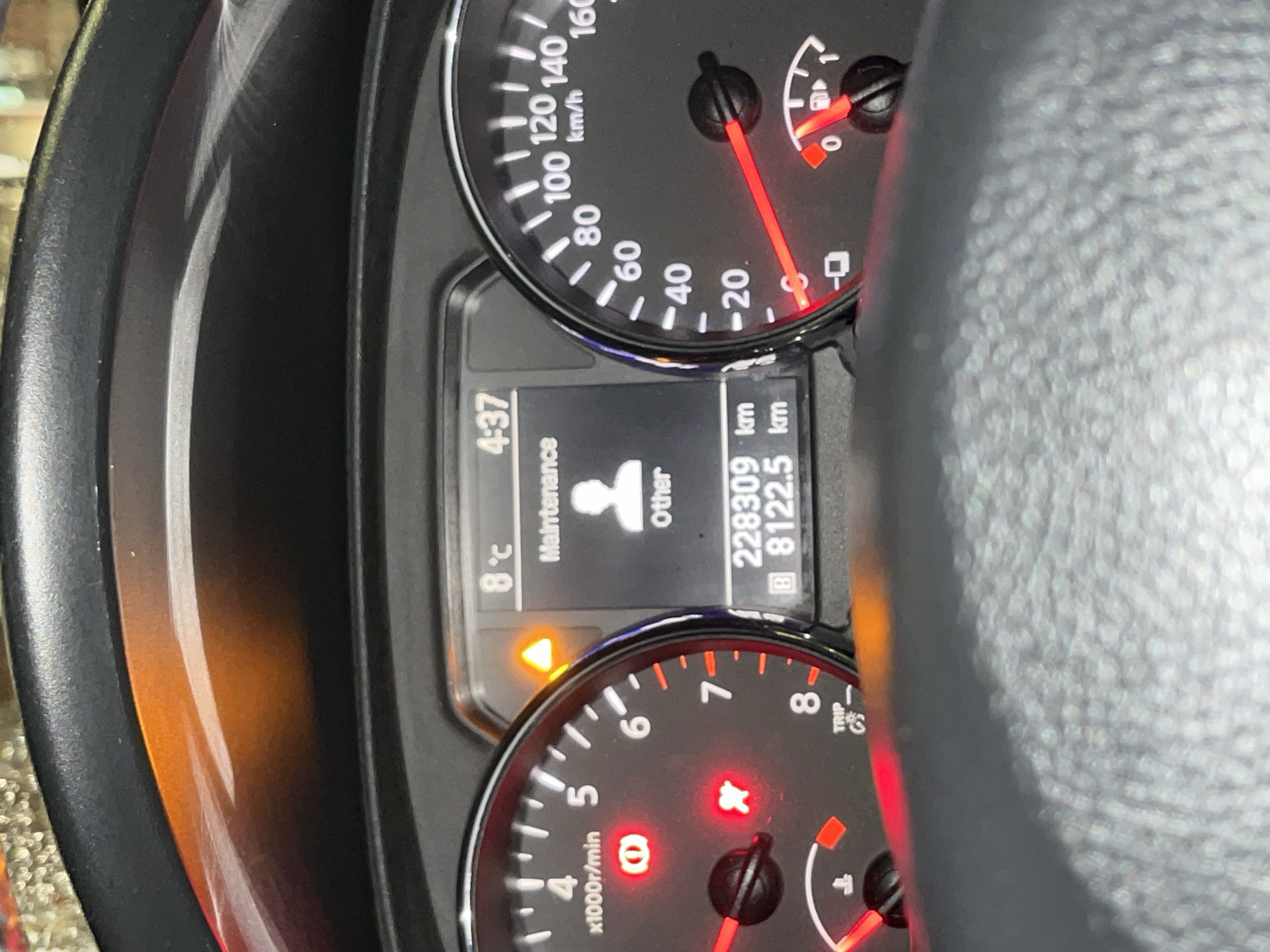 The image shows a car dashboard. The speedometer reads approximately 5 km/h. The digital display shows "Maintenance Other" and a mileage of 228309 km. The outside temperature is 8°C, and the time is 4:37. An orange warning light is illuminated. The tachometer needle is near 1,000 RPM. There is no indication of the location being Sofia, Bulgaria.