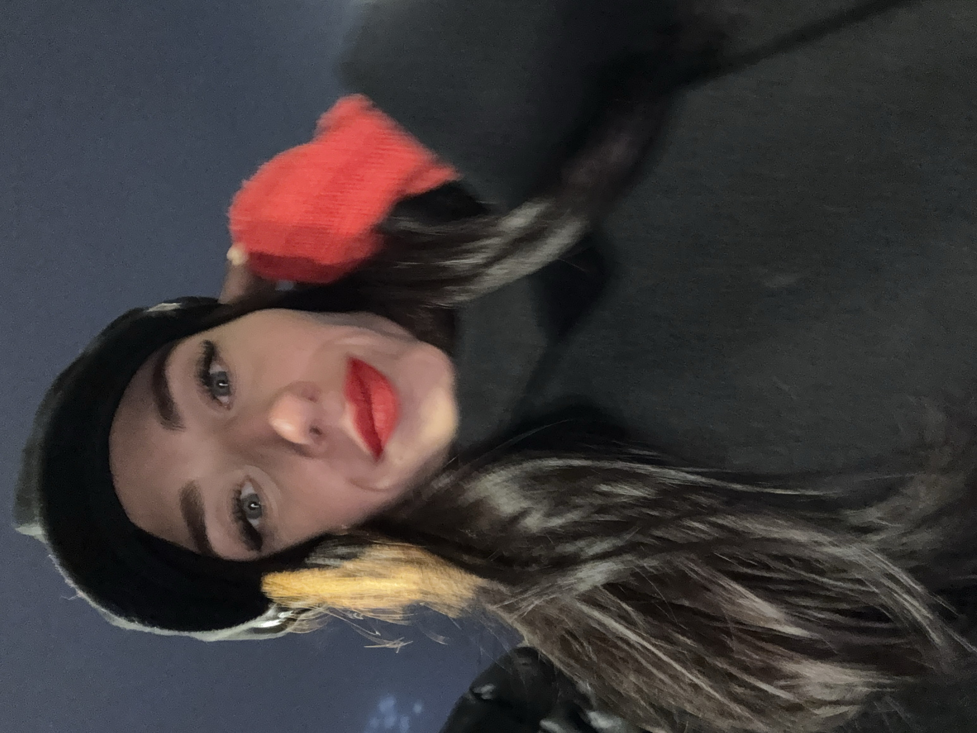 A young woman wearing a black beret and a dark coat is visible in the image. She has dark hair with highlights, light eyes, and red lipstick. A red glove is partially visible in the upper portion of the frame. The background suggests an outdoor setting, possibly in the city of Saint Petersburg, Russia, though there are no specific landmarks visible to confirm the location.