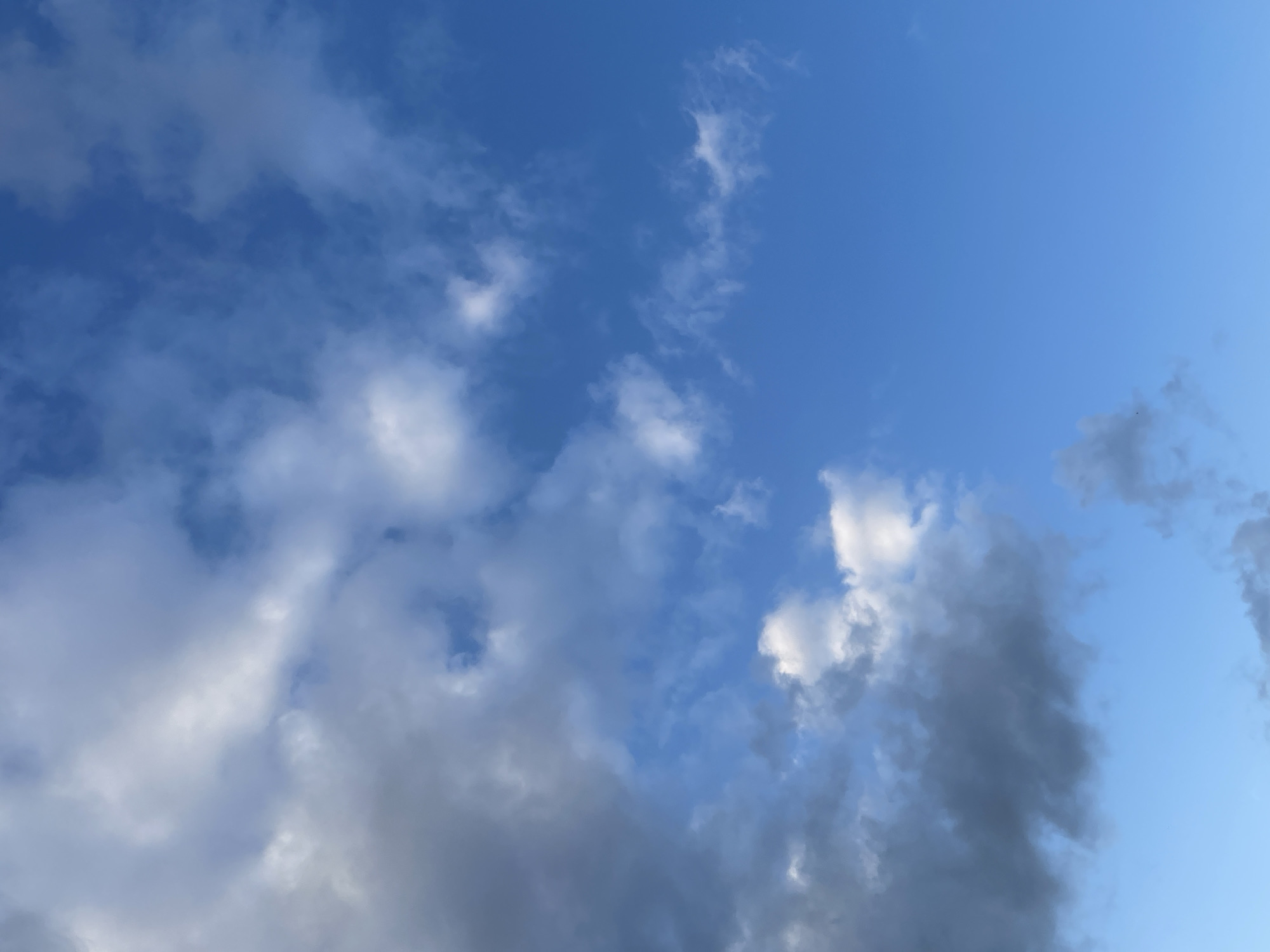 The image shows a sky with clouds and blue sky. There are some dark gray clouds on the left side of the image, and lighter white clouds scattered throughout the blue sky on the right. The image does not contain any elements that would indicate a location in Moscow, Russia, or any other specific city. There are no people, subjects, objects, or actions depicted in the image. The environment is simply a sky.