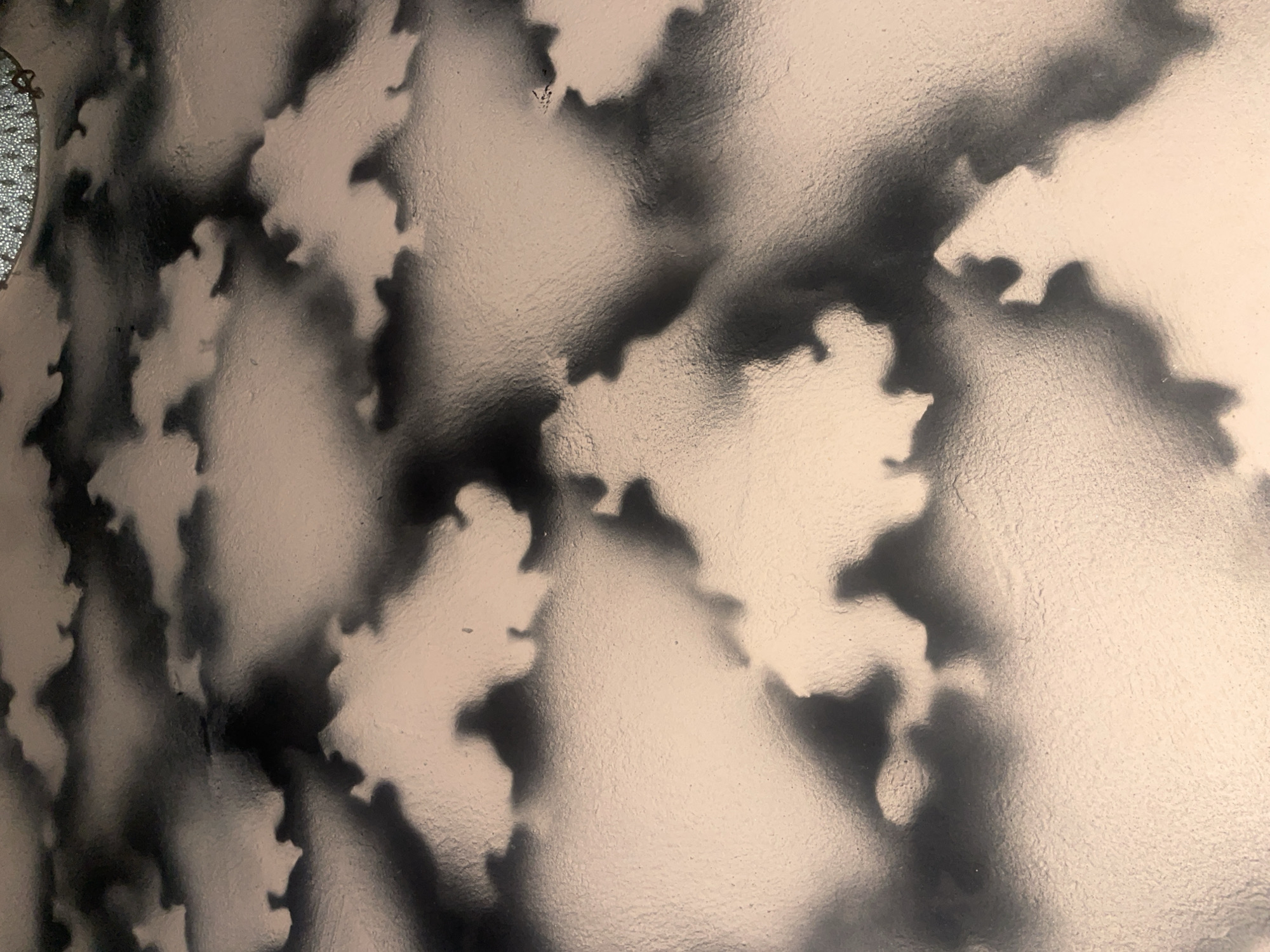 The image depicts a close-up, overhead view of a textured surface with a mottled pattern of light beige and dark grey. The pattern resembles clouds or smoke, with soft, blended edges between the two colors. The texture of the surface appears slightly rough or porous. There are no discernible people, objects, or specific environmental features visible within the frame that would allow for identification of a location in Ihiagwa, Nigeria. The image is abstract and lacks contextual details.