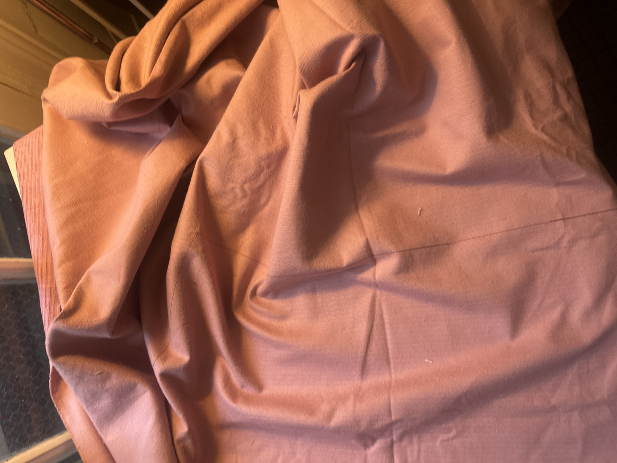 The image shows a close-up view of a wrinkled, rose-colored fabric. The fabric's texture appears soft and possibly corduroy. The lighting suggests an indoor setting. No people or specific objects are discernible. The location in Buenos Aires, Argentina is not evident from the image.