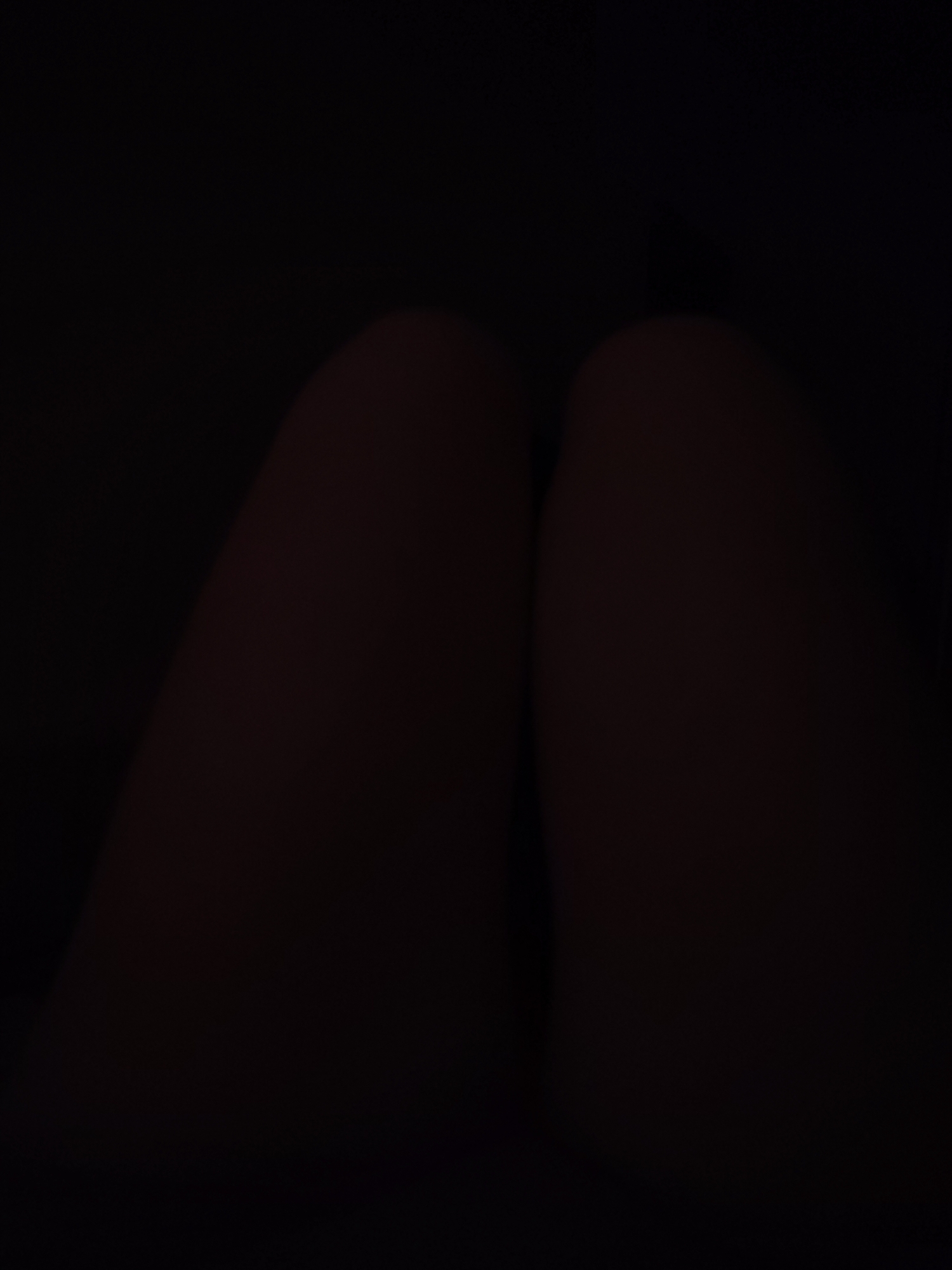 The image shows a close-up view of two human thighs in low lighting conditions. It is difficult to determine any details about the environment or location, including whether it is in Izhevsk, Russia, due to the darkness and lack of identifiable features.