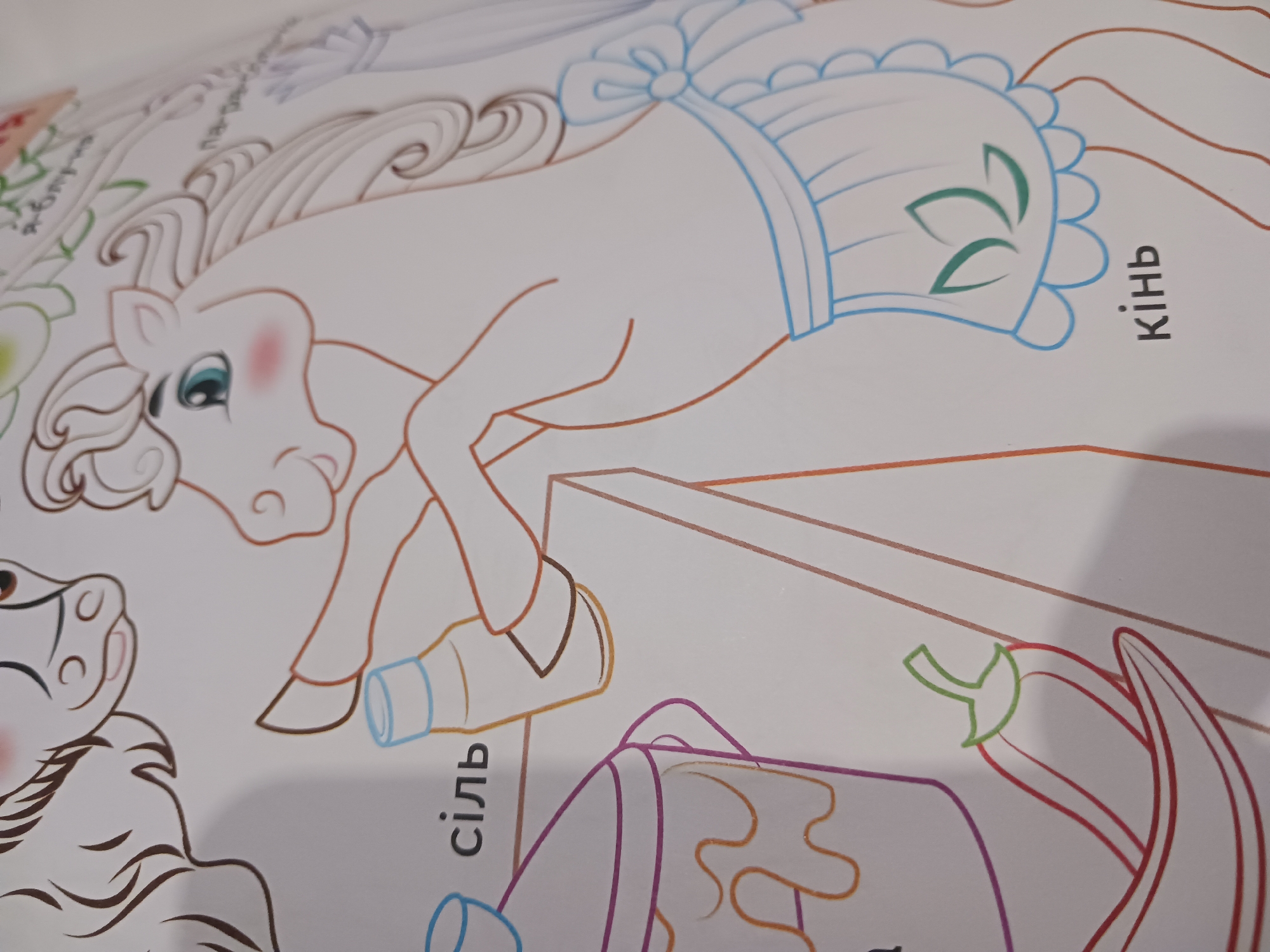 The image shows a coloring book illustration of a horse with a ruffled apron and a plant motif. In the foreground, a red pepper is depicted. To the left, a pot is partially visible, and next to it is a bottle and text in Cyrillic. The word "сіль" is visible, which translates to "salt." Further to the right, the word "кінь" is visible, translating to "horse." The overall scene is of an agricultural or domestic setting, with the horse appearing to be involved in some activity related to food preparation or storage. The illustration style is simple and line-based, typical of a coloring book.
