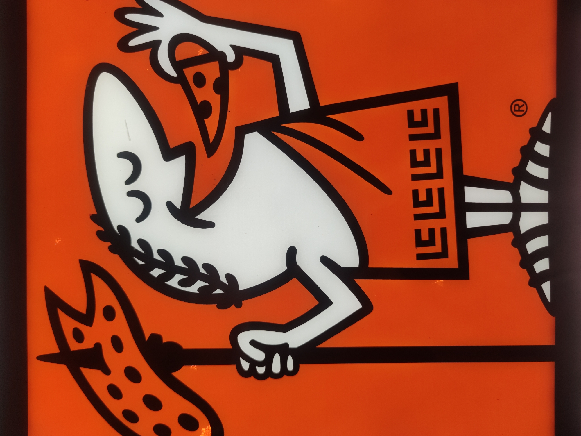 An animated, stylized Roman emperor with white skin, black eyes, and a laurel wreath is depicted against an orange background. He is holding a spear topped with a pepperoni pizza slice. The emperor is wearing a red toga with a black border featuring a Greek key pattern. He is also shown holding a slice of pizza to his mouth. The bottom of the image displays the emperor's feet and a trademark symbol. The overall style is cartoonish and appears to be a logo for a pizza company. The setting is not discernible from the image.