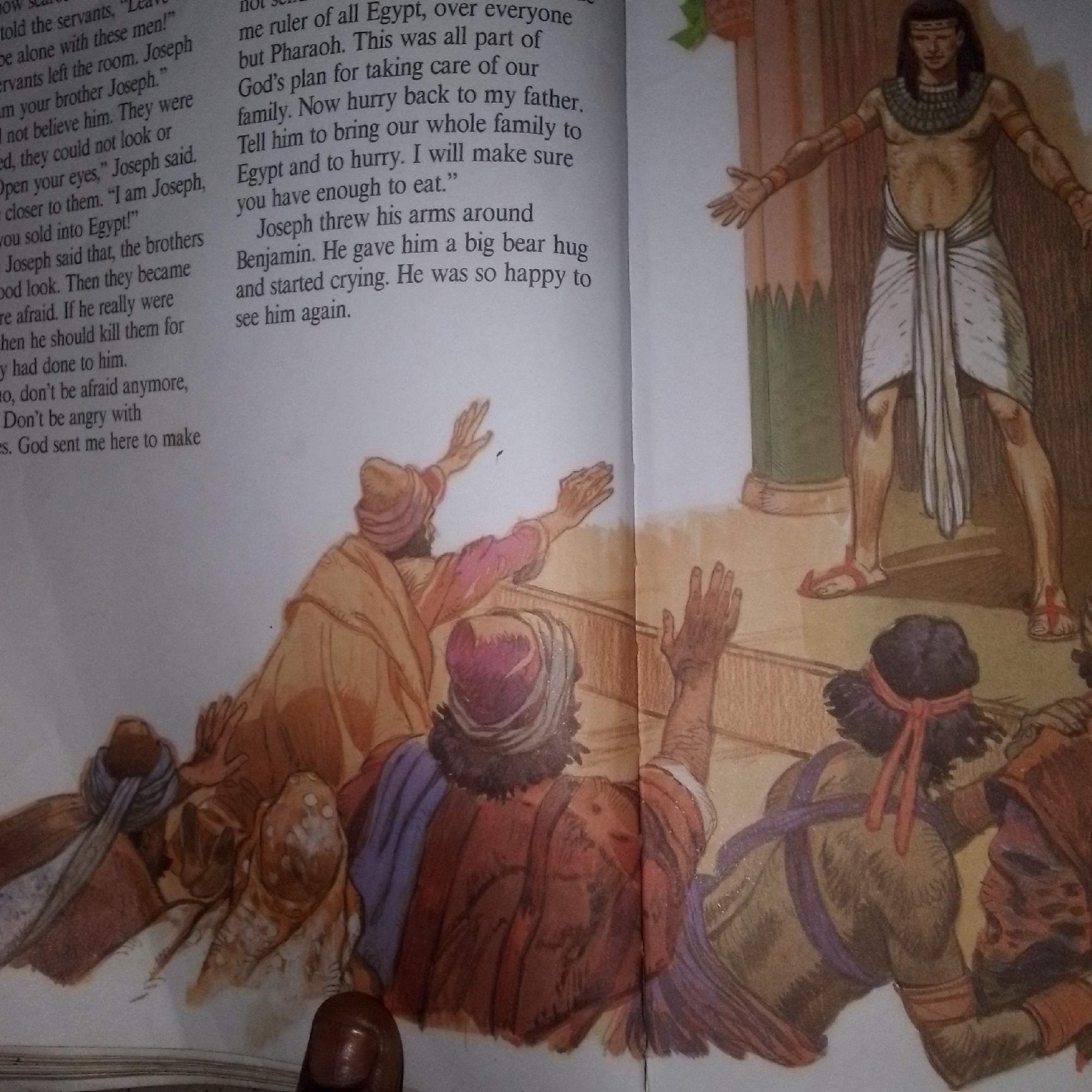The image depicts an illustration from a book. On the left side of the page, there is text describing a biblical narrative, likely the story of Joseph. The text mentions characters like Joseph, Benjamin, and Pharaoh. The right side of the page features an illustration of a historical or biblical scene. A man, presumably Pharaoh, stands with his arms outstretched, wearing a white kilt and a distinctive necklace. In front of him, several individuals in similar attire are depicted in varying states of distress or supplication, with their hands raised. The illustration style suggests a traditional or religious context. The image does not contain any information about Jalingo, Nigeria.