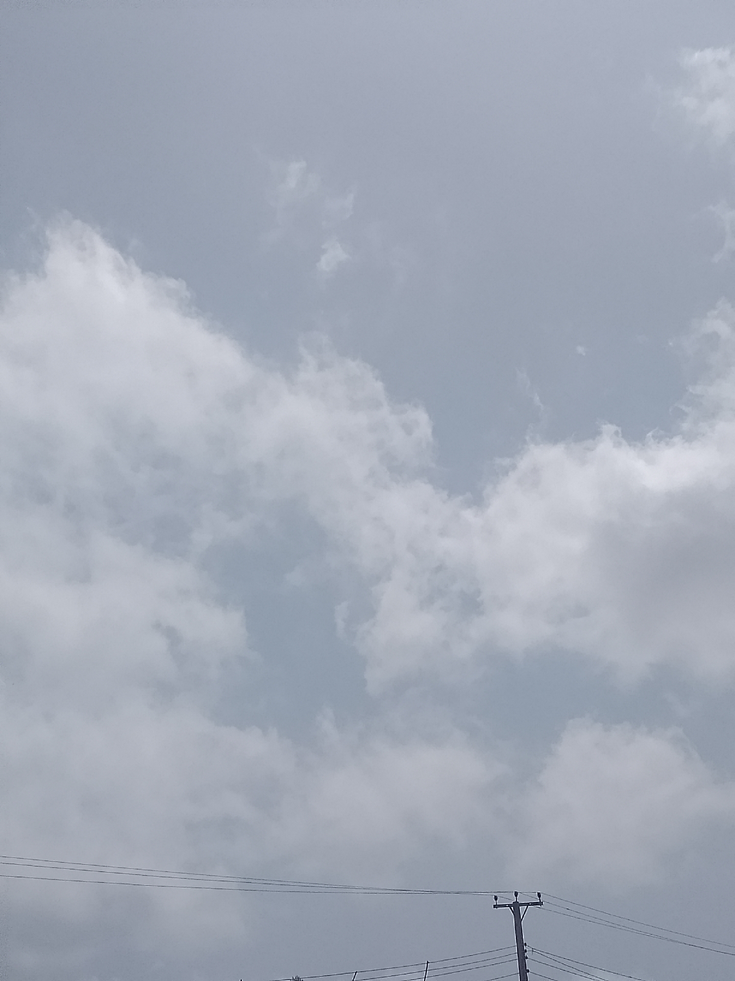 The image shows a cloudy sky in Barikin Sabon Gidan Kanat, Nigeria. A utility pole with power lines is visible at the bottom of the frame.
