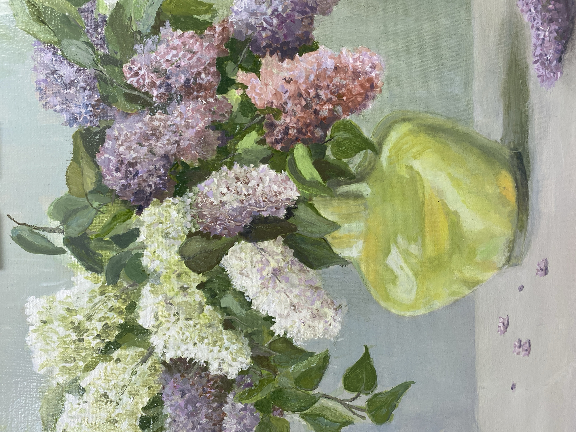 This is a close-up, oil painting still life of a bouquet of lilacs in a bright green vase. The lilacs are a mix of white, pale purple, and pinkish hues, with green leaves interspersed throughout. The vase is bulbous with a glossy finish, reflecting light. The bouquet is arranged in a way that suggests movement and fullness. The background is a muted, light green, and the foreground shows a neutral-colored surface with a few fallen lilac florets. There are no people, animals, or identifiable landmarks in the painting. The location of Ivanteyevka, Russia, is not depicted or inferable from the image.