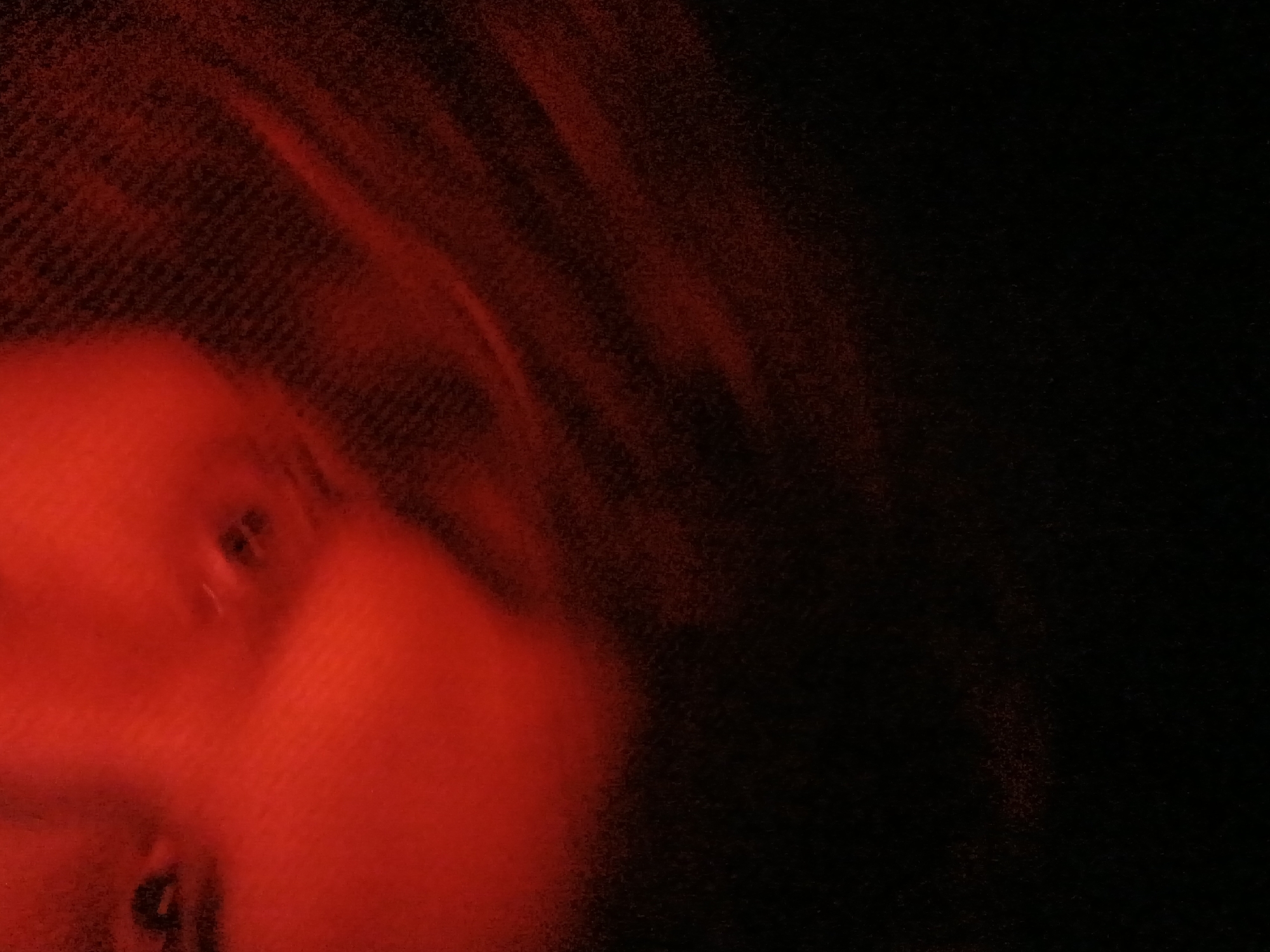 A blurry, low-light image predominantly in shades of red and black. The image appears to feature a portion of a person's face on the left side, with indistinct facial features. The right side of the image is largely black, with some indistinct red streaks. There is no clear indication of a location within Buenos Aires, Argentina, or any specific actions, interactions, or identifiable objects.