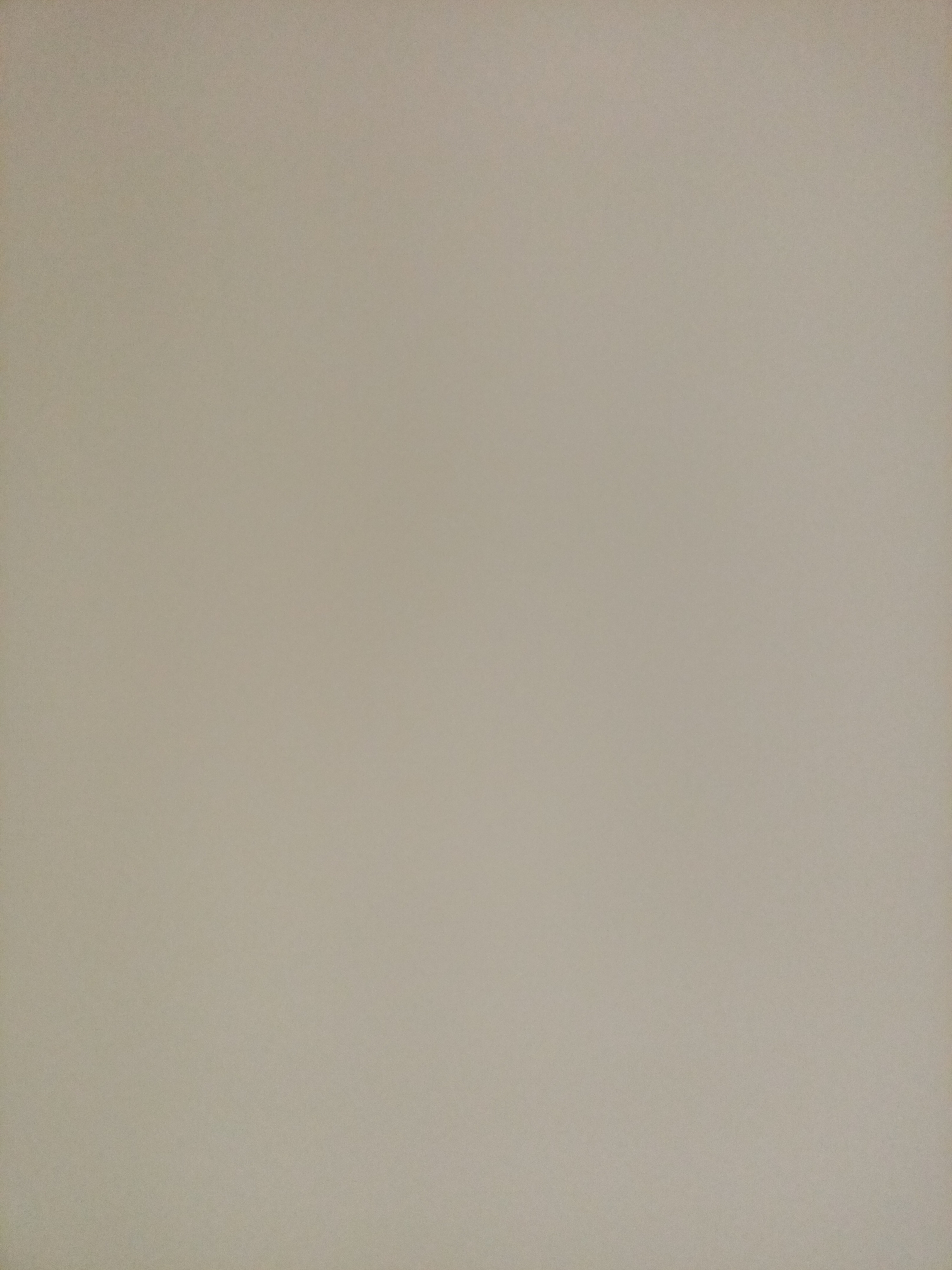 The image is a close-up shot of a light beige, textured surface, possibly a wall or paper. There are no people, objects, or discernible features within the frame. The lighting appears uniform, casting no shadows. The background is a solid, neutral color.