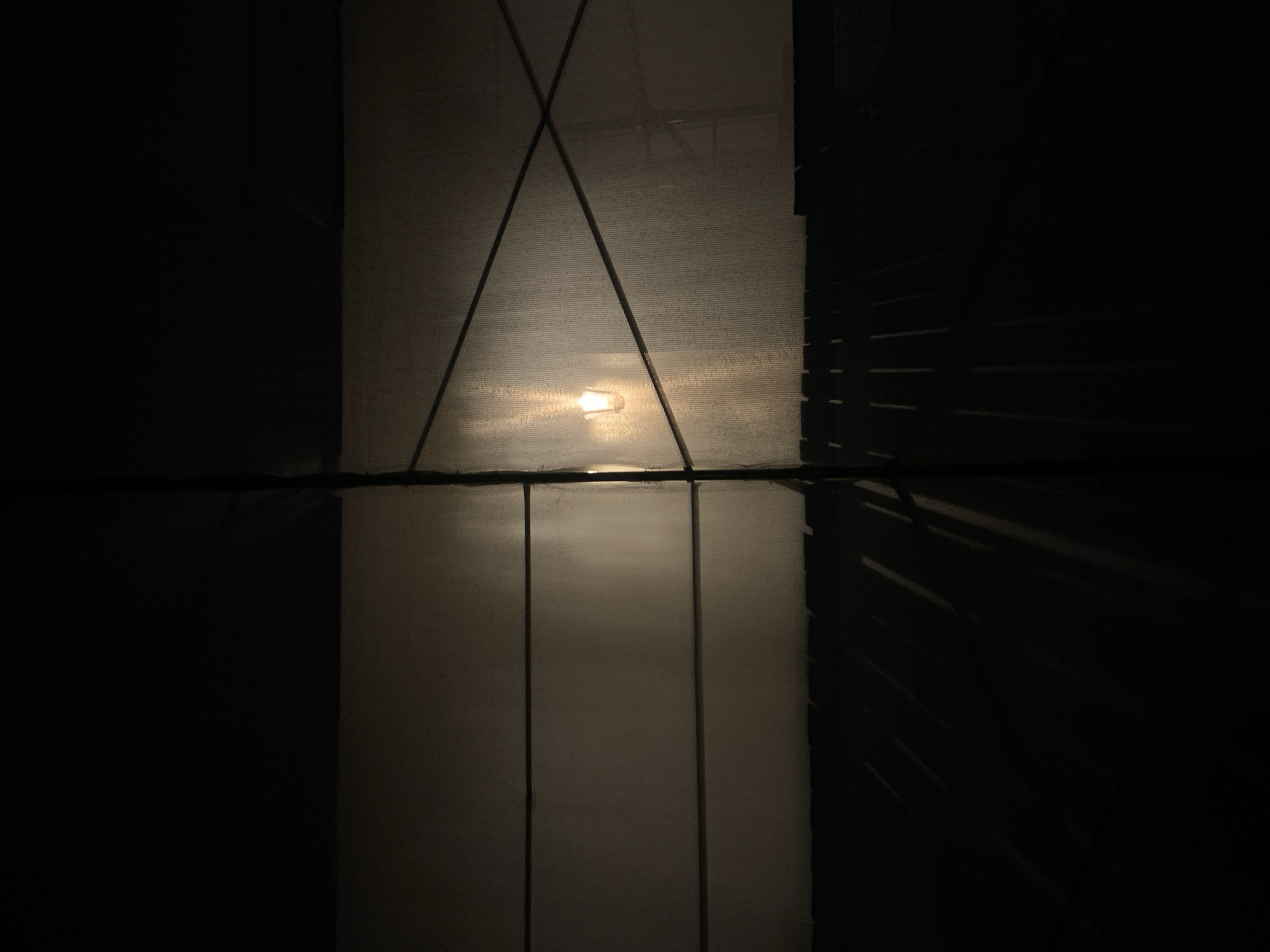The image shows an interior view with a translucent material covering a window or opening. A light source is visible through the material, casting a diffused glow. There are dark lines that intersect and create shapes on the material. One light source is illuminating the translucent material in the opening, located in Moscow, Russia. The other objects in the image appear dark and undefined.