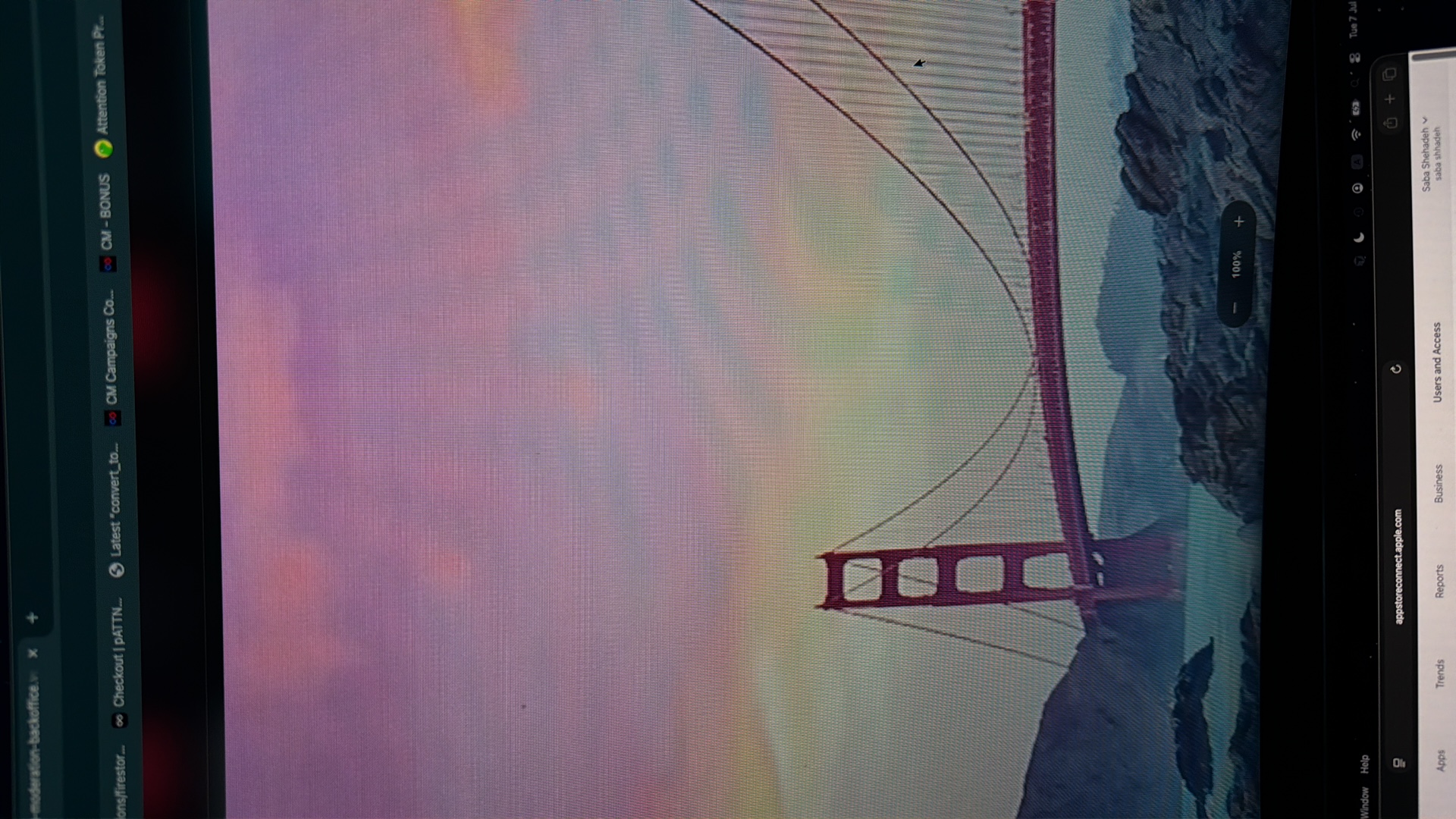 The image shows a screenshot of a computer screen displaying a wallpaper of the Golden Gate Bridge. In the foreground, the iconic red suspension bridge is visible against a backdrop of purple and pink sky. The lower part of the screen shows a black bar with website information and icons, including "appstoreconnect.apple.com". There is no indication of the city of Kafr Yasif, Israel in the image.