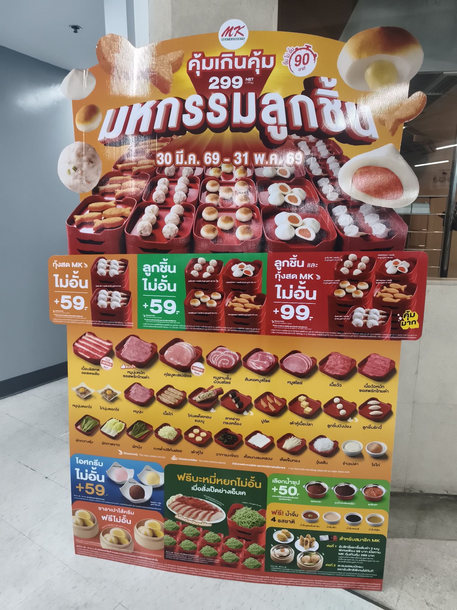 The image shows a promotional poster for MK Restaurants in Baan Bo Phut, Thailand. The poster advertises an "All You Can Eat" promotion with a variety of meat and vegetables. Included in the images are shrimp and meat dishes that can be made into the all-you-can-eat plan for different prices. The promotion runs from March 30 to May 31 of 2069. It also includes free refills of drinks, sauces, and noodles. Special deals for MK members are mentioned at the bottom.