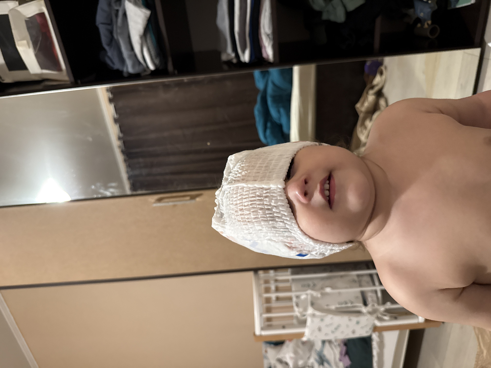 A child with a diaper on their head is visible, with a closet and other items in the background. The location is indeterminate; there is no evidence of Tobolsk, Russia.