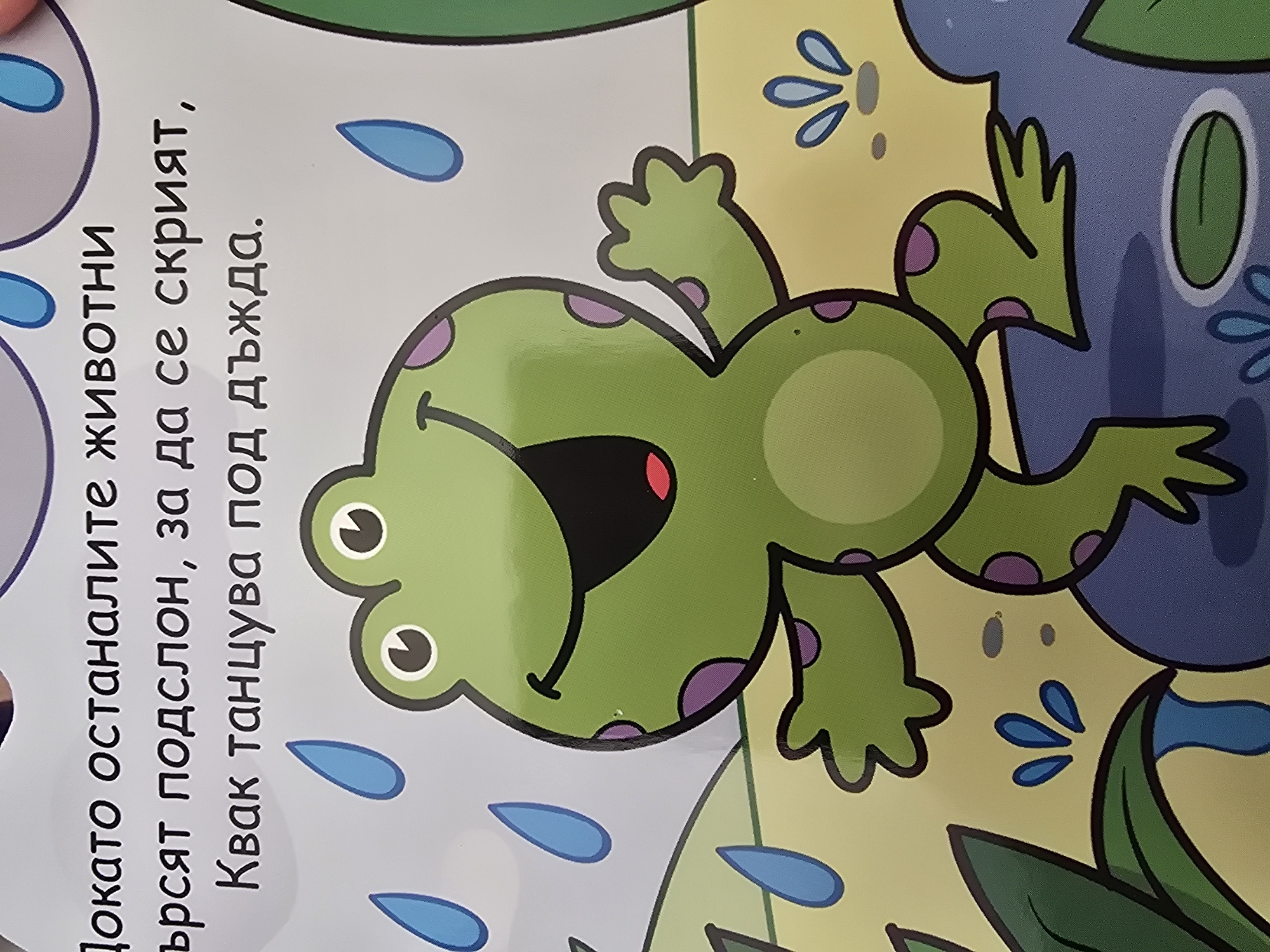 Here is a description of the image:
The image shows a cartoon illustration of a green frog with purple spots, positioned next to Bulgarian text on the left side of the frame. The frog is smiling and appears to be in a playful pose, with its limbs extended outwards. It has a red area inside its mouth, and white circles with black pupils as eyes. Blue raindrops are scattered around the frog and the text. The background features areas of yellow, green, and blue, suggesting a watery environment with plants. The text is written in Cyrillic script, indicating it is Bulgarian. The overall scene is colorful and whimsical, typical of a children's book or educational material.