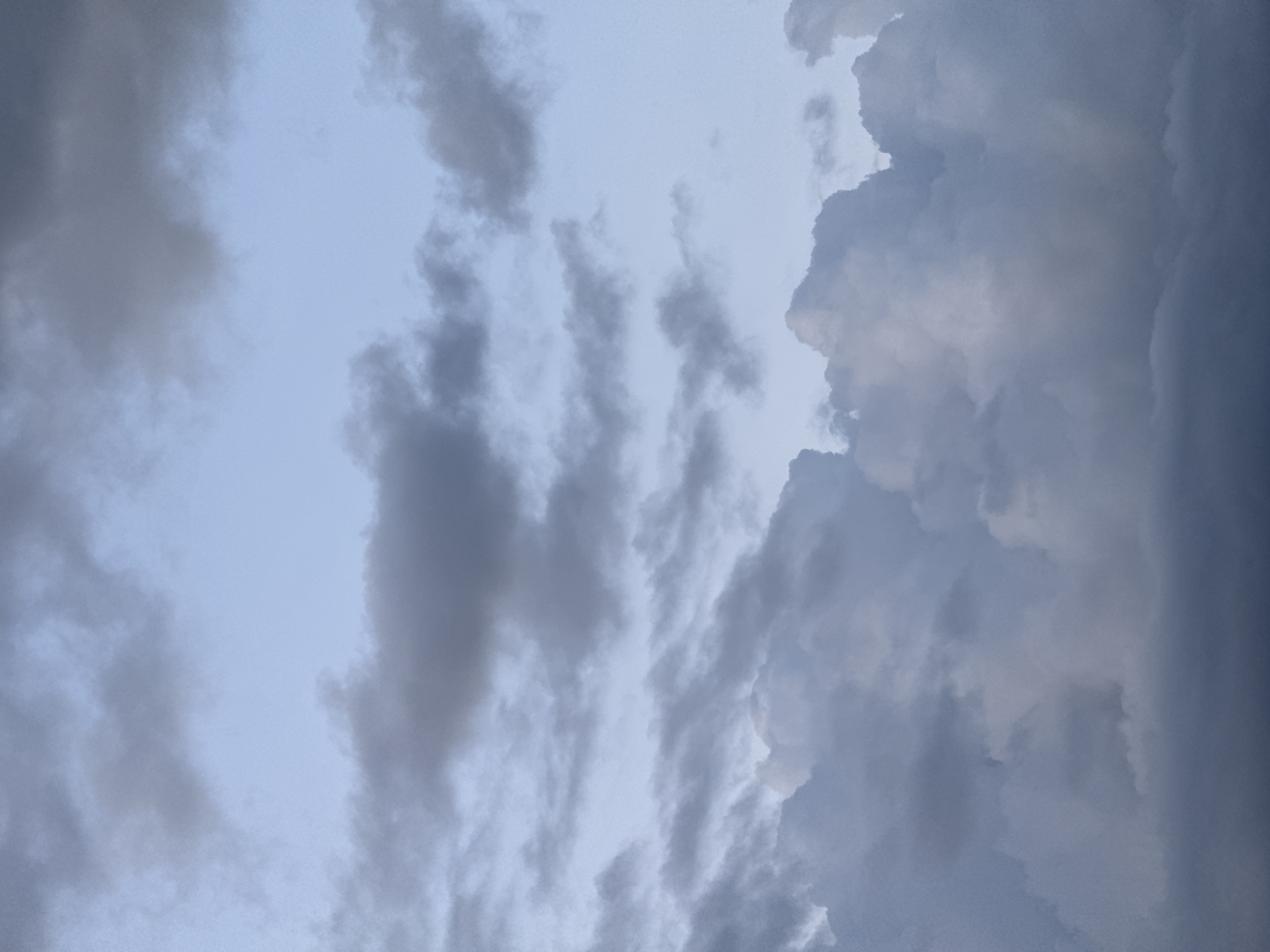 The image shows a close-up view of a cloudy sky. The clouds are varied in density and color, ranging from dark gray at the bottom to lighter grays and blues towards the top. There are no people, subjects, or objects visible in the frame, only the atmospheric elements. The lighting suggests it is either early morning or late evening. The location is identified as Бараўлянскі сельскі Савет, Belarus, indicating a rural or suburban setting where such a sky would be observed.