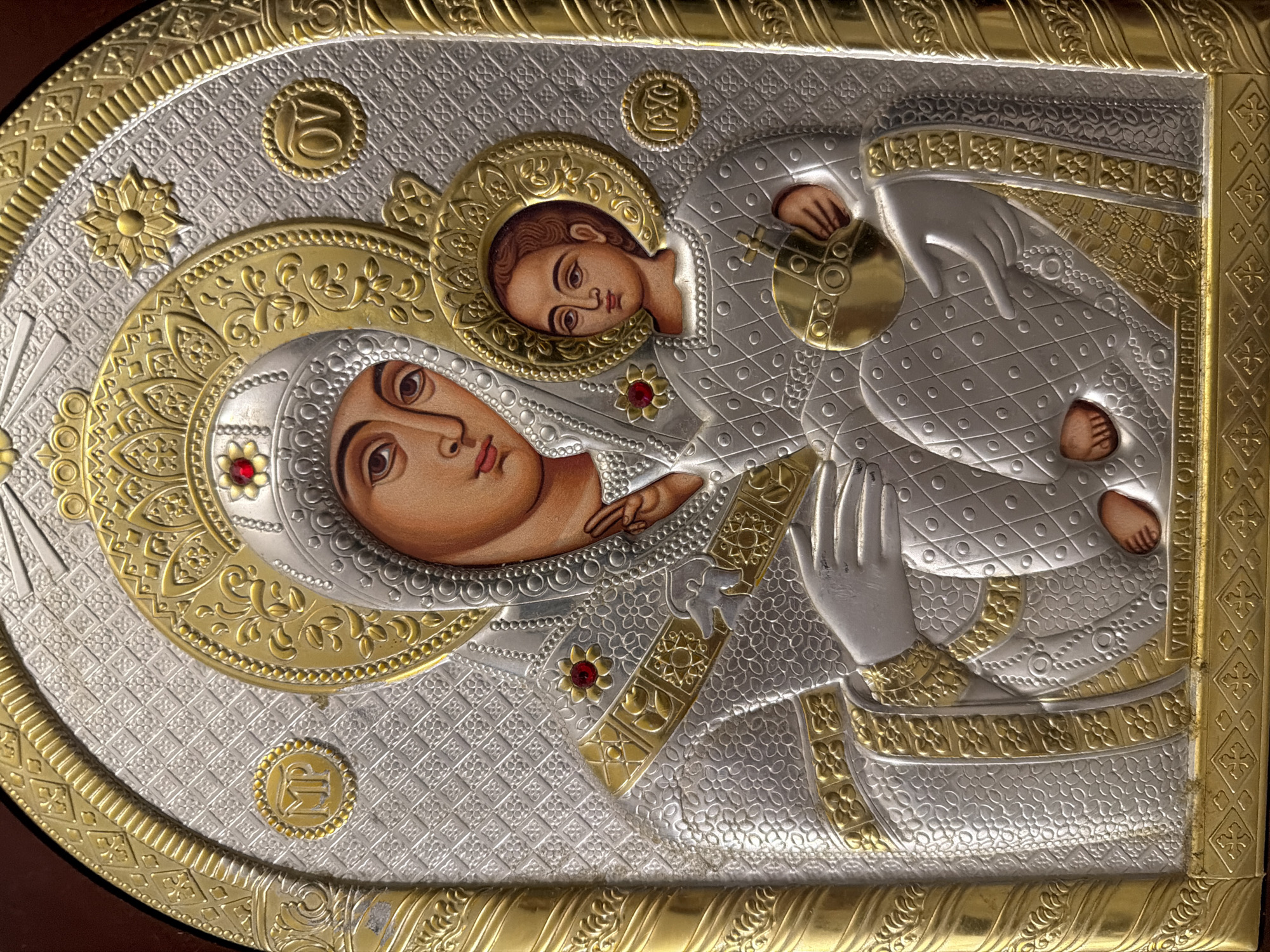 The image shows an icon of the Virgin Mary and the Christ Child, likely an Orthodox Christian icon, as indicated by the halos and inscriptions. The figures are depicted in a devotional pose, with Mary cradling the child. The icon is framed by ornate gold metalwork with intricate patterns. There are religious symbols and inscriptions present on the icon. The text at the bottom of the icon reads "VIRGIN MARY OF BETHLEHEM". There is no information in the image or its crops that suggests a location in the city of Tallinn, Estonia.