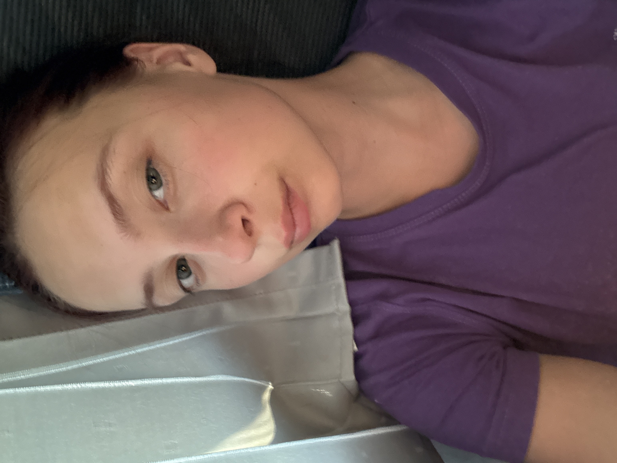 A young woman is lying down, her head resting on a pale, possibly satin, surface. She is wearing a purple shirt. The background appears to be a dark corduroy surface. The location, Staryi Chul'tem, Russia, is not visually confirmed in the image.
