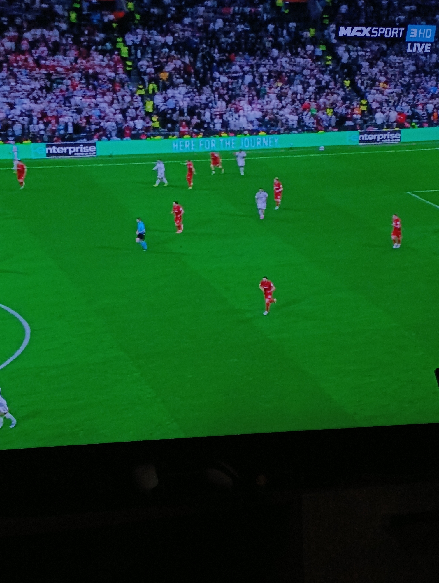 The image shows a soccer game in progress, broadcast live on MaxSport 3 HD. The pitch is green, with several players visible in red and white uniforms. A referee in dark clothing is also present. There's a large crowd in the background, and advertising banners reading "Enterprise" and "Here for the Journey" are visible along the sideline. The location is suggested to be Plovdiv, Bulgaria, though there are no specific geographical identifiers in the image to confirm this.