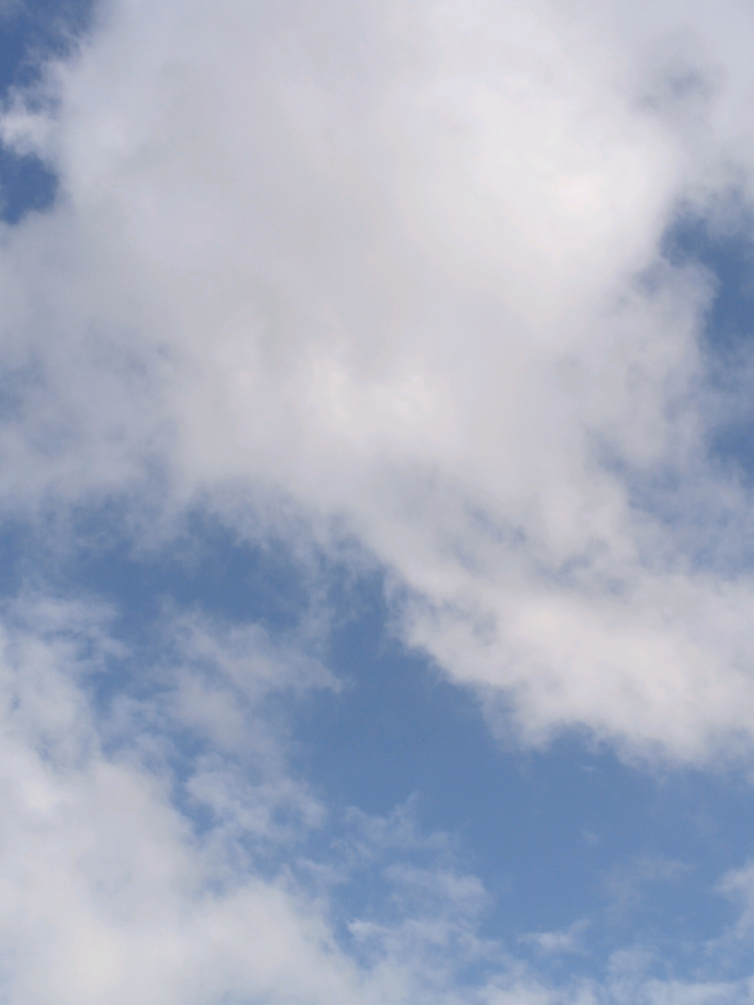 The image is a close-up, full-frame photograph of a sky filled with clouds and blue sky. There are no discernible landmarks, structures, people, or objects that would indicate a specific location in Denpasar, Indonesia, or any other city. The image solely depicts the atmospheric conditions of a cloudy sky.