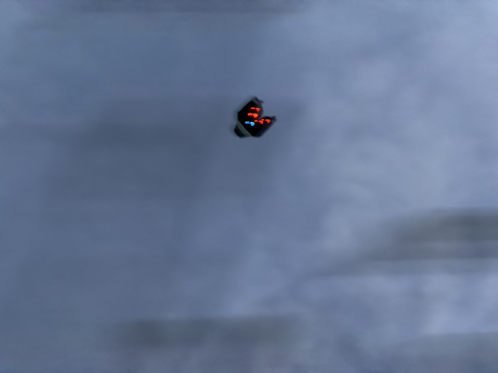 The image shows a blurry, butterfly-shaped object with red and blue lights hovering in the air against a cloudy, grey sky. It is not possible to confirm if the location is North Kuta, Indonesia or to provide further details about the scene based on this image.