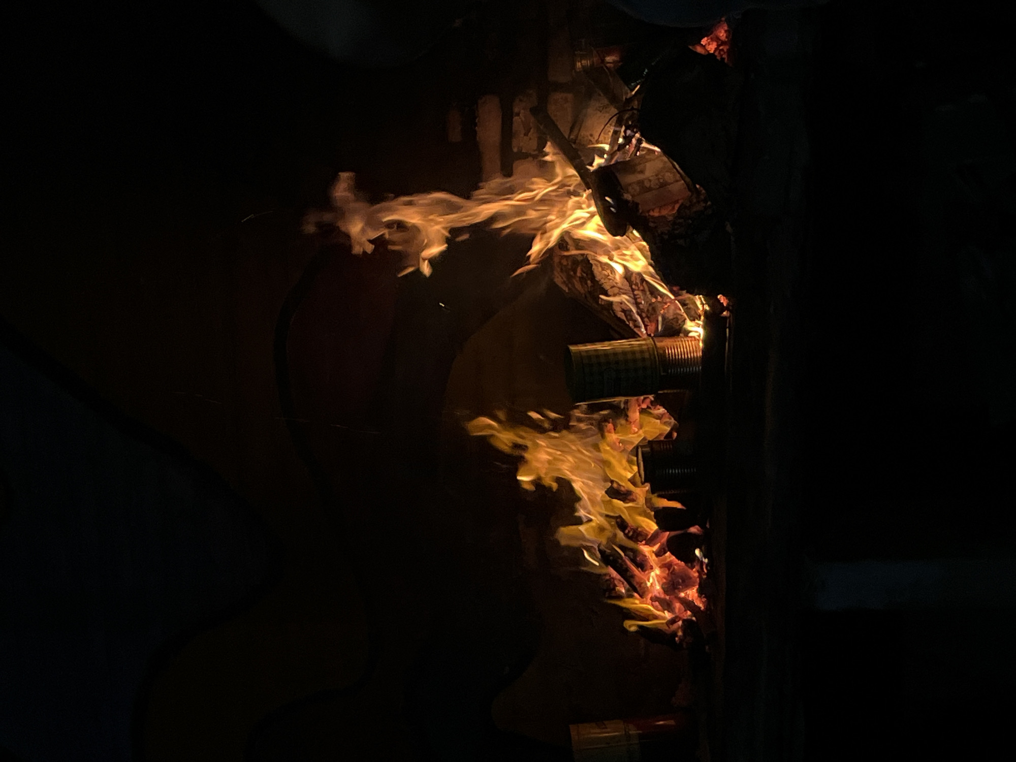 A vertical, low-light photograph shows a fire burning in what appears to be a metal container. The flames rise upward, illuminating the container and the surrounding area. The location, Buenos Aires, Argentina, cannot be verified from this image. There are no people visible in the image.