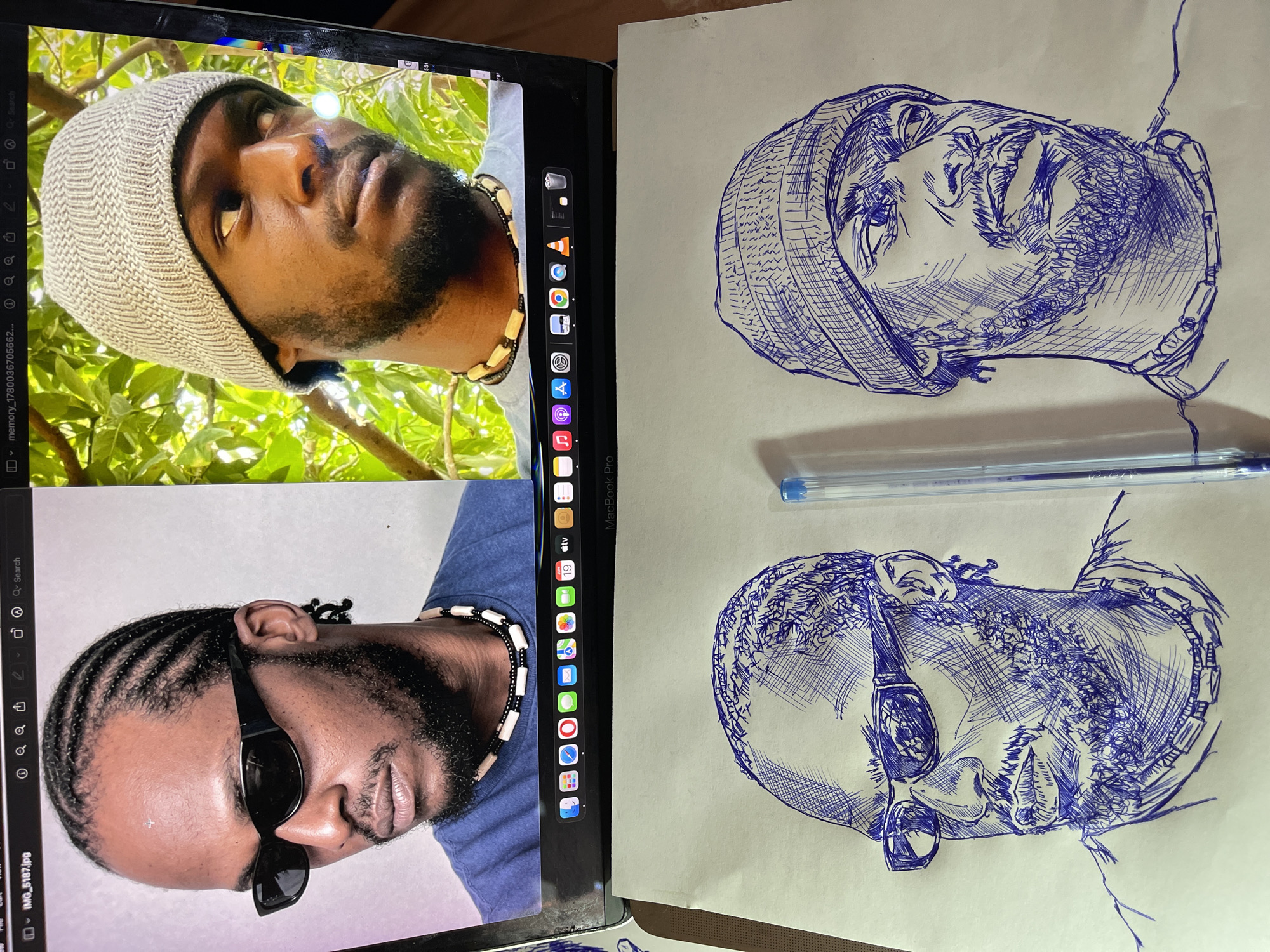 The image displays two portraits of the same Black man, one on a laptop screen and two ink sketches below it. The man has dark skin, a beard, and wears a necklace. In the laptop image, the man is shown in two different poses. In the left portrait, he wears sunglasses and has cornrows. In the right portrait, he wears a knitted beanie and looks to the side. The sketches are rendered in blue ink and depict the man's face and upper body, closely resembling the laptop images. One sketch shows him wearing sunglasses and the other wearing the beanie. A blue pen lies horizontally between the two sketches. The background of the laptop image features green foliage. The overall scene suggests an artistic process of replicating images through drawing. There is no identifiable information to determine the location of Jos, Nigeria.