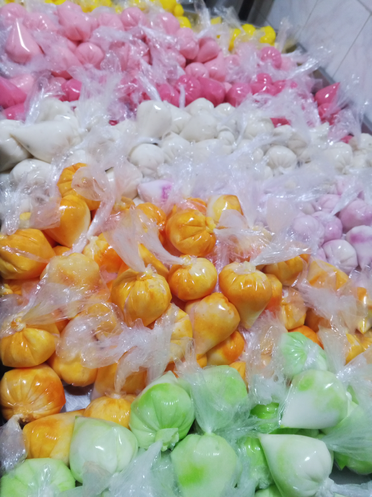 The image shows a close-up of multiple small plastic bags filled with liquids of various colors arranged in rows. The colors include yellow, pink, white, orange, lavender and green. The bags are likely arranged in a tray or container.
The information about Tinaquillo, Venezuela is not visually discernible from the image.
