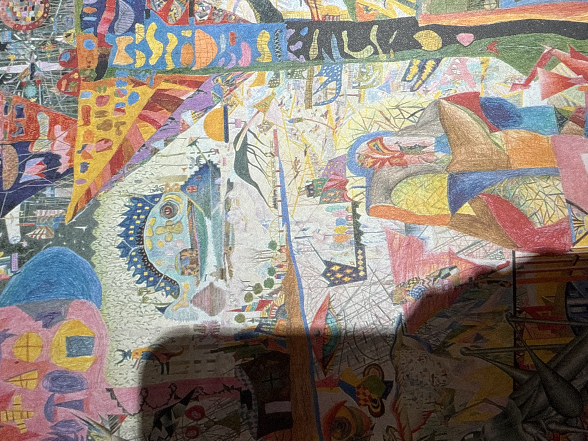 The image is a detailed, colorful drawing with a surreal and imaginative style. It depicts a fantastical cityscape with various architectural elements, abstract shapes, and whimsical creatures. There are no clear landmarks or indications that place this scene specifically within Moscow, Russia. The drawing features a jumble of vibrant colors and intricate patterns, with elements that could be interpreted as buildings, boats, bridges, and possibly fantastical beings. The overall impression is one of a dreamlike or otherworldly landscape.