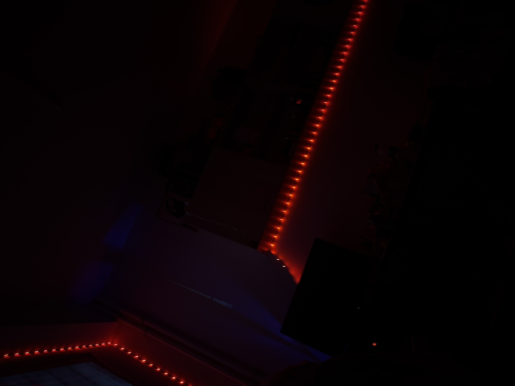 The image depicts a dimly lit interior space. Red LED strip lights are affixed to the walls and possibly the ceiling. A monitor or screen is visible, partially obscured by darkness. Other objects and details are indistinct due to the low lighting. There is no clear indication of a specific location in Sofia, Bulgaria.