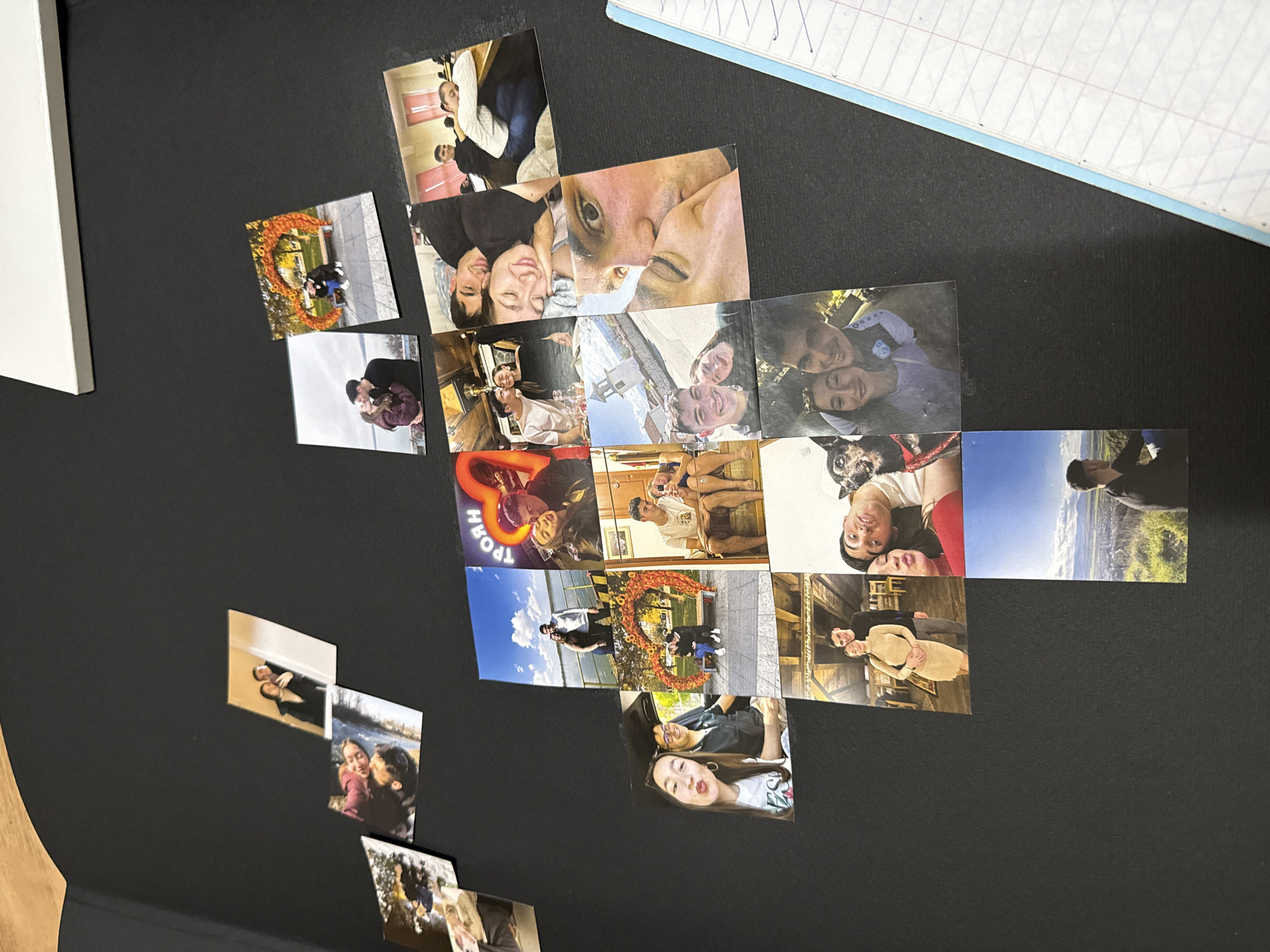 A collection of approximately 20 square printed photographs is arranged in a rough diamond shape on a dark-colored surface. The photographs appear to depict a young couple in various settings. Subjects range from close-up portraits to full-body shots in outdoor locations with vegetation. Some scenes include people in indoor settings. The photograph featuring a large floral heart is the closest to the city of Sofia, Bulgaria, although there isn't a matching location for it. The overall aesthetic suggests a personal collection of memories.