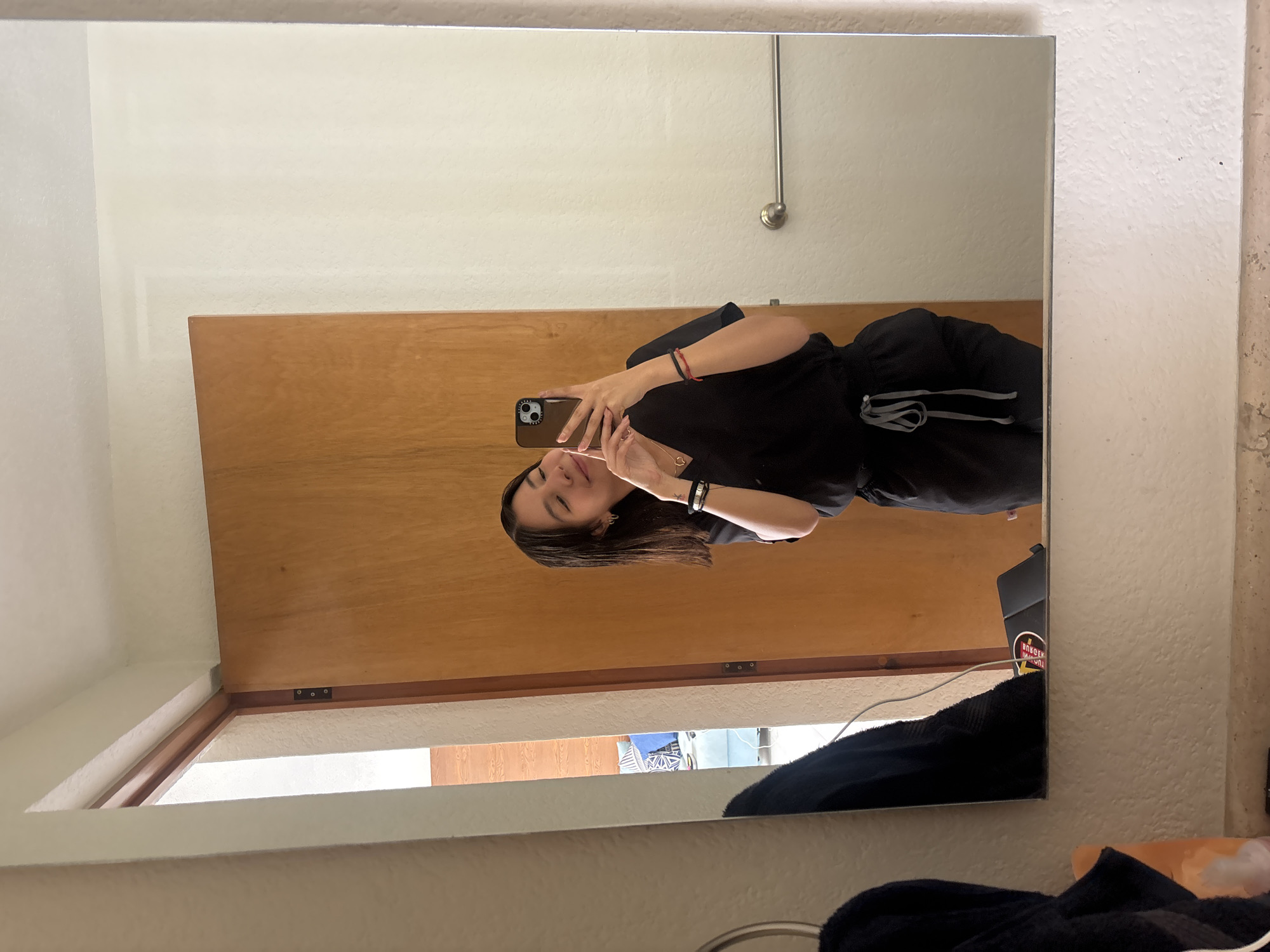 A woman is taking a selfie in a mirror. The background shows a wooden door and part of a window. There is a towel and a laptop on a surface below the mirror. The location is indicated to be in the city of Puebla, Mexico but this is not discernible from the image content alone.
