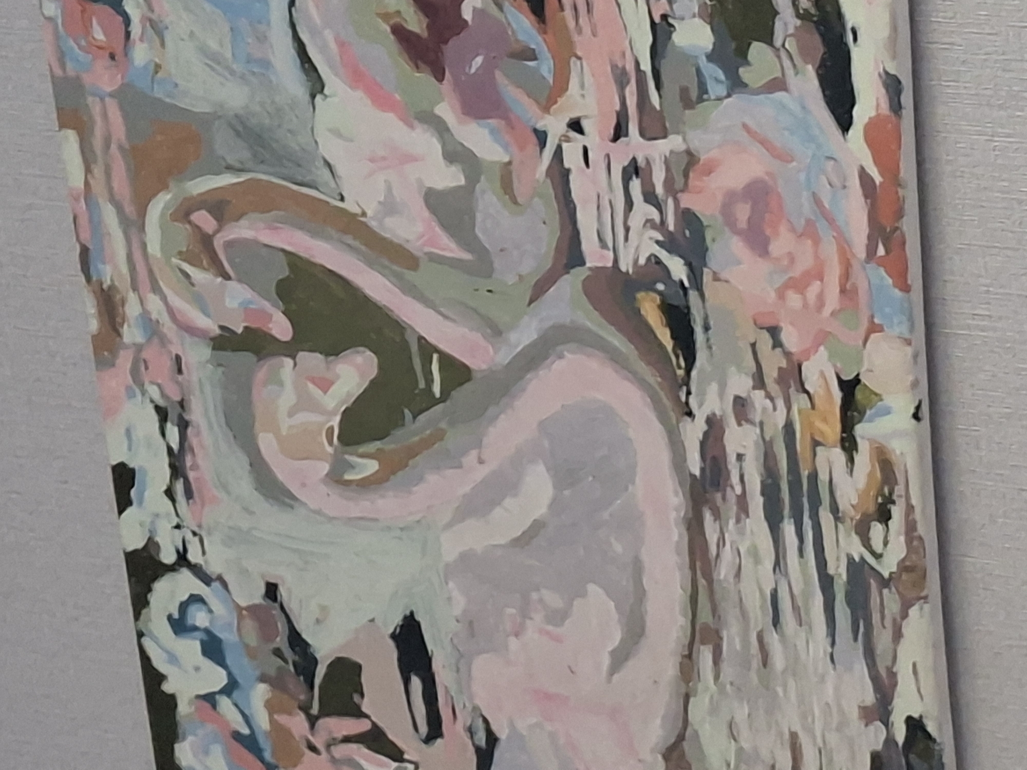 The image is a close-up of a painting depicting two swans in water. The swans' necks are intertwined, forming a heart shape. The painting uses a pastel color palette with shades of pink, white, blue, and green, giving it a soft and dreamlike quality. The water is rendered with abstract brushstrokes, suggesting ripples and reflections. In the foreground, there are hints of flowers, also depicted in soft colors. The background is a blend of abstract shapes and colors, creating a textured and somewhat impressionistic effect. The painting appears to be a "paint by numbers" artwork, given the distinct areas of color and the simplified rendering of forms. There is no identifiable location in Shymkent, Kazakhstan, or any other specific geographic setting depicted in the image.
