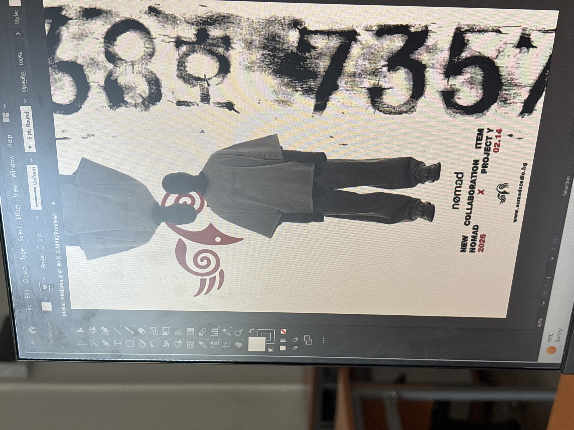 The image shows a computer screen displaying a digital design project in Adobe Illustrator, likely an advertisement poster, given the file name "plakat reklama.ai". The screen is oriented vertically within the photograph.
The main subjects of the design are two stylized human figures, depicted as silhouettes or models, wearing oversized, light-colored clothing. They appear to be facing each other. The figure on the right has "nomad" printed on its clothing. Above these figures, large, distressed black numbers "68" and "7357" are prominently featured. Below the figures, a red, swirling graphic or logo is visible.
Visible text on the design includes "NEW COLLABORATION", "NOMAD 2026", an "X", "ITEM", "PROJECT Y", and "02.14" (possibly a date). A website address, "www.somadstudio.bg", is also present. The user interface of Adobe Illustrator is visible, showing menu bars ("File", "Edit", "Object", "Type", "Select", "Effect", "View", "Window", "Help"), toolbars on the left, and panels on the right displaying settings like "Opacity: 100%", "Uniform", and "5 pt. Round" for strokes. The bottom of the screen shows part of the Windows taskbar, including a weather widget indicating "11°C Sunny". The activity captured is a person engaged in graphic design work. The image is a photograph of a screen, exhibiting some glare and pixelation.