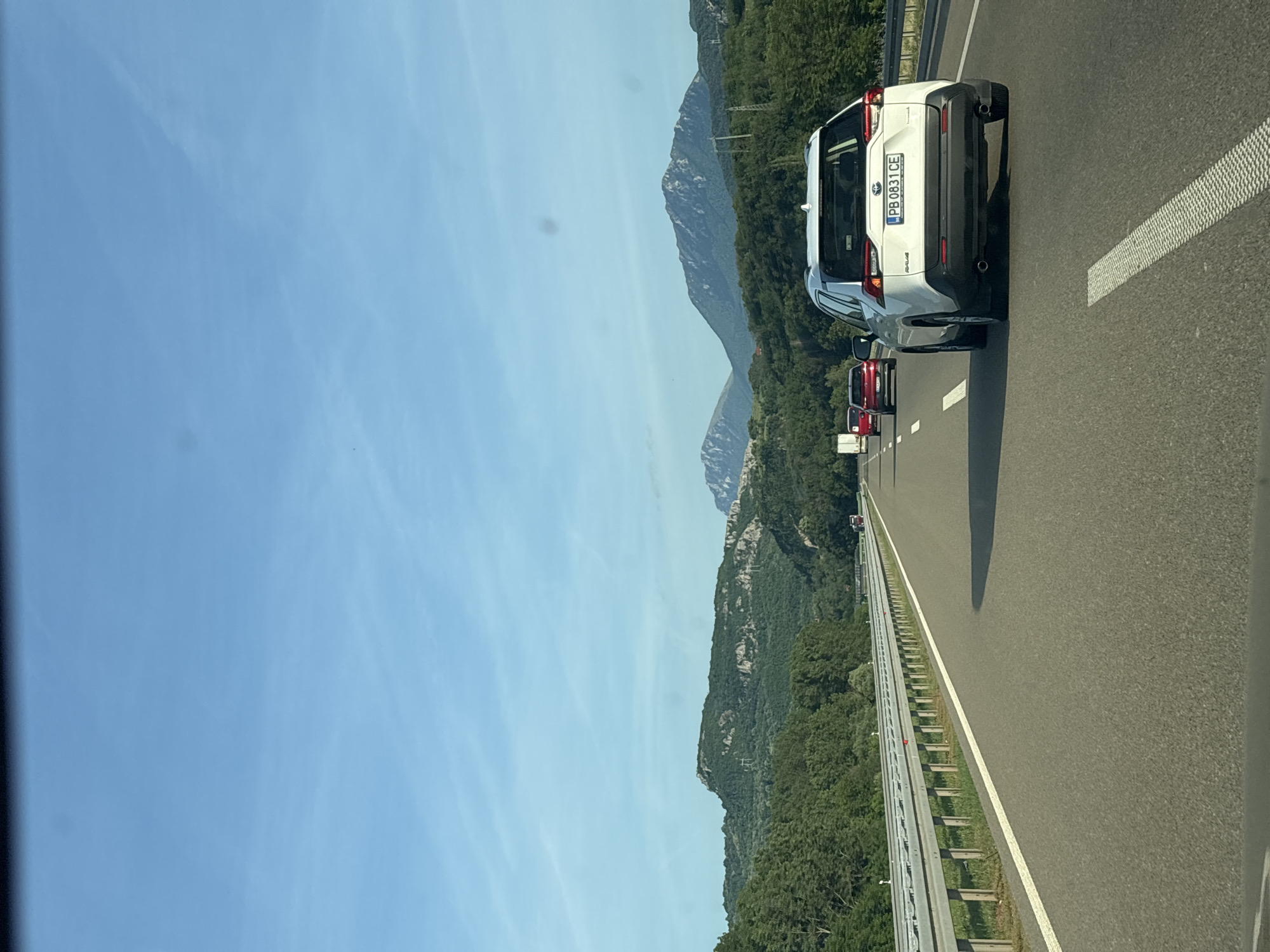 The image shows a highway in Serbia, specifically within the Градска општина Нишка Бања region. A white Toyota RAV4 is prominently featured in the right lane, with the license plate "PB 0831 CE". Other cars, including at least one red vehicle, are visible further ahead in the same lane. The highway is lined with a metal barrier and green vegetation on the side. In the background, mountains are visible under a clear, blue sky.