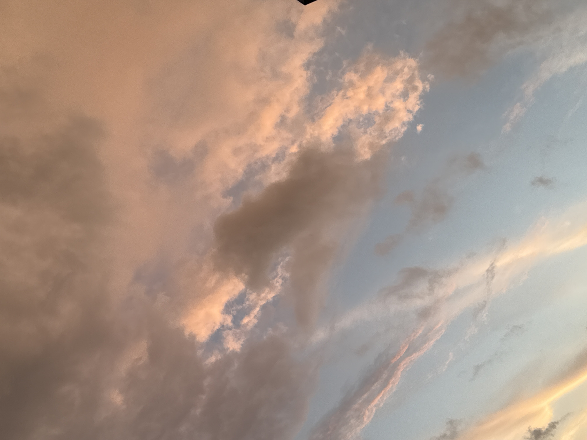 The image shows a cloudy sky with warm hues of orange and pink, suggesting a sunset or sunrise. The clouds are varied in texture and density, with some appearing wispy and others more solid and textured. The sky transitions from a soft orange at the top of the frame to a lighter blue towards the bottom. There are no people, subjects, or objects clearly identifiable in the image besides the clouds and the sky. The scene depicts a natural, atmospheric phenomenon and does not provide specific information about the city of Lyubertsy, Russia, or any particular location within it.