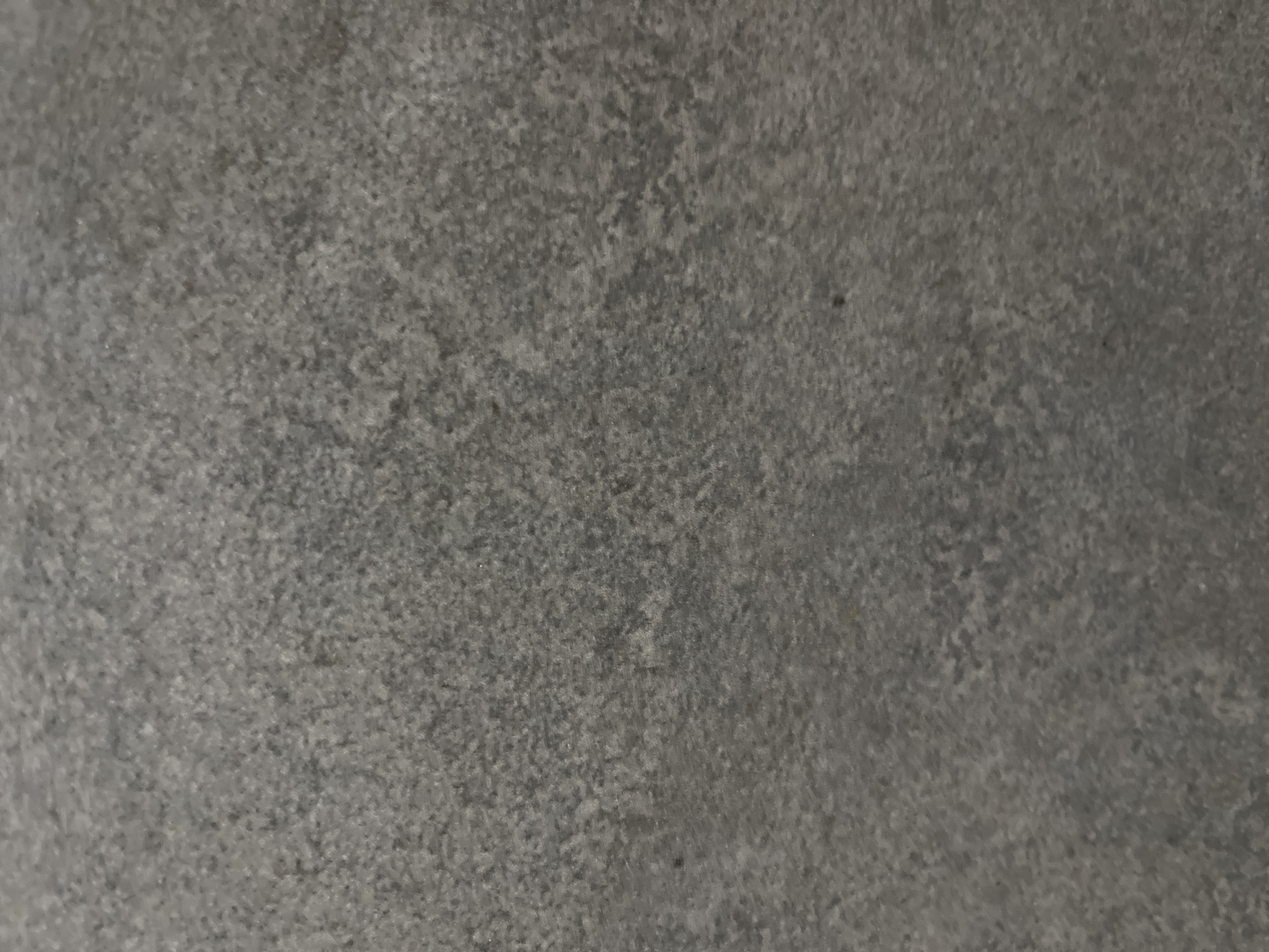 The image is a close-up, full-frame shot of a gray, textured surface, resembling concrete or stone. There are no discernible objects, people, or actions present. The lighting is even, and the texture appears consistent throughout. The image does not contain any identifiable landmarks or features that would allow for its localization within Kyiv, Ukraine.