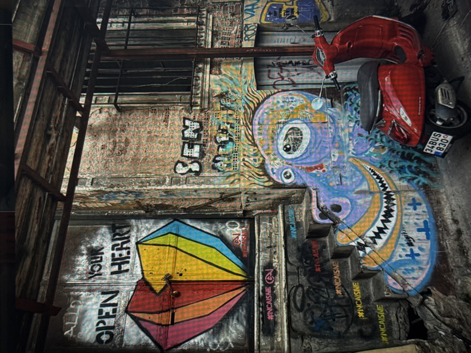 This media file captures a vibrant street art scene in Eyüpsultan, Turkey, featuring a red scooter parked in front of a graffiti-covered brick wall. The wall is adorned with large, colorful murals, including a psychedelic depiction of a creature with a large eye and a sharp-toothed mouth. Below this, a segment of a rainbow-colored shape is painted, with the words "OPEN HEART" and "YOUR" also visible in bold black lettering. The scooter itself has a license plate that reads "34BUS 8300," a common format for Turkish license plates, with "34" indicating Istanbul.
The overall impression is one of urban decay juxtaposed with creative expression. The peeling paint and weathered brick suggest an aged environment, while the bold graffiti injects life and color. The time of day is not explicitly indicated, but the lighting suggests it could be daytime. There are no people visible in the frame, focusing all attention on the static elements of the scene. The graffiti tags and hashtags like "#INCAISME" suggest a contemporary art context, common in urban exploration and street art photography. The scene evokes a sense of artistic vitality in an otherwise possibly neglected urban space.