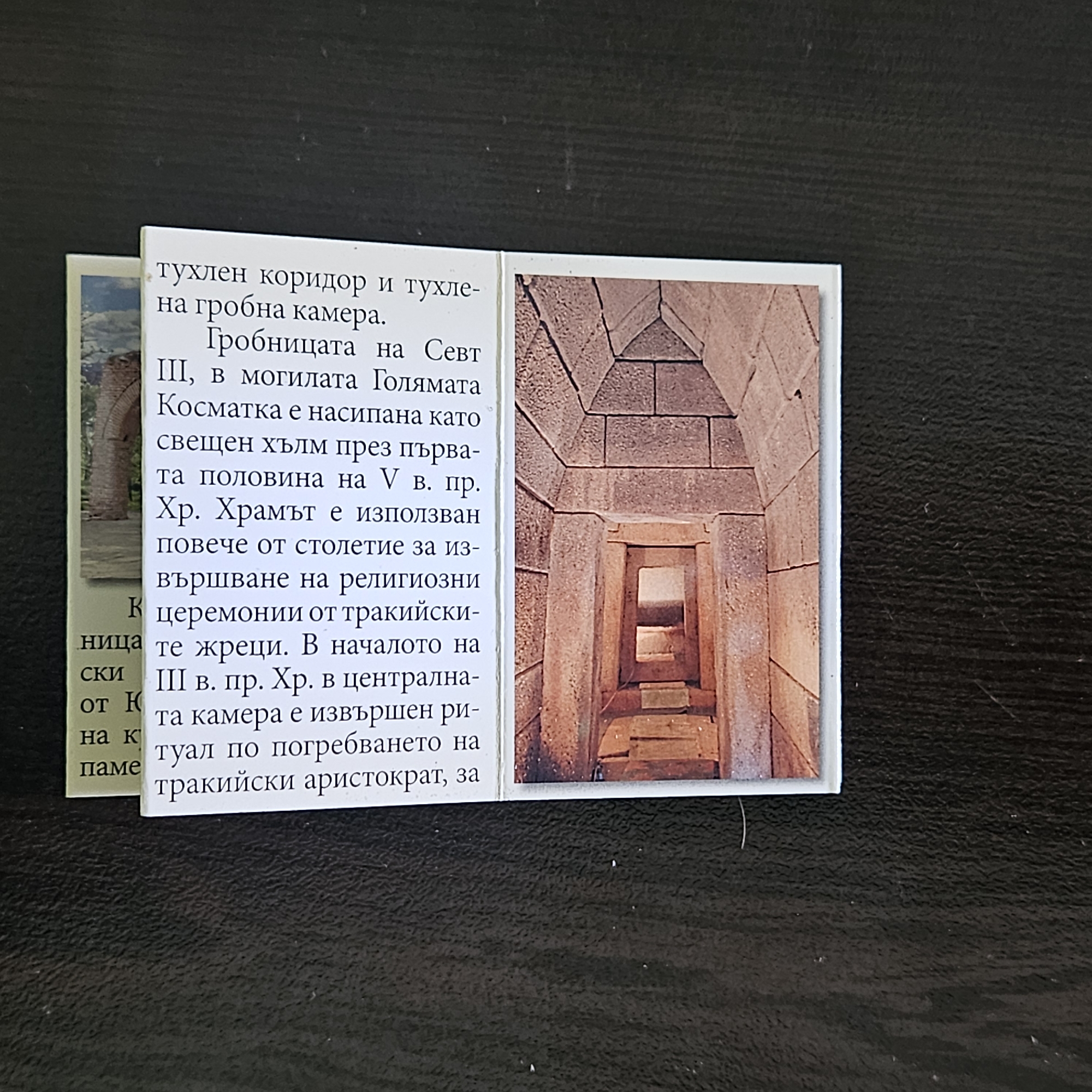 The image shows a close-up of two adjacent cards. The card on the right displays a color photograph of a stone structure, seemingly an interior view. The architecture features a tunnel-like entrance, built with rectangular stone blocks. The card on the left contains Bulgarian text describing a tomb and temple, likely related to the image. The text mentions the tomb of Seuthes III, situated in the Golyama Kosmatka mound, near Stara Zagora, Bulgaria. It notes the temple's use for religious ceremonies and the performance of burial rituals for a Thracian aristocrat in the 3rd century BC.