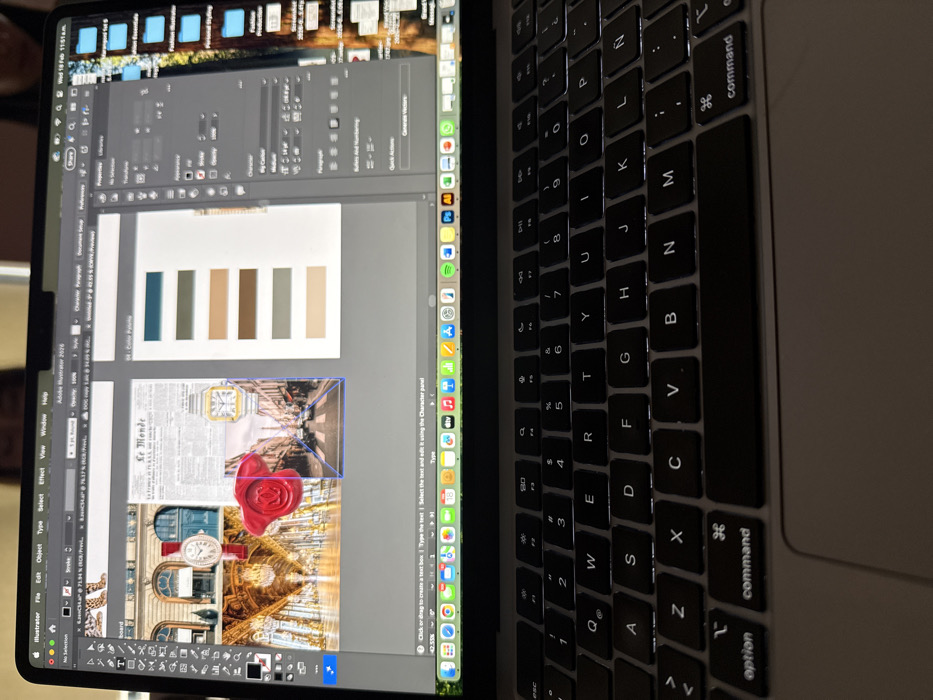 The image displays a MacBook laptop open and viewed from a high-angle perspective, tilted slightly to the side. The laptop's screen is illuminated, showing design software, while its backlit keyboard is visible on the right side of the frame.
On the laptop's screen, Adobe Illustrator is open and actively being used for a graphic design project. The main workspace features an artboard containing several visual elements. At the top of the artboard, there is a color palette consisting of five rectangular swatches in varying shades of blue-green, brown, and beige. Below this, two distinct layouts are visible. The top layout features a section of an old newspaper, partially obscured, with "Le Monde" clearly visible as its title. Superimposed on or next to the newspaper section is an image of a gold-colored rectangular wristwatch. The lower layout shows a collage of architectural elements, featuring ornate classical buildings, possibly from a European city, and a large red wax seal or rose object. One of the building sections also displays another watch, circular this time, integrated into the architecture. A selection box with blue outlines is visible around part of the image content, indicating active selection.
The Adobe Illustrator interface is rich with panels and tools. The top menu bar shows "Illustrator File Edit Object Type Select Effect View Window Help". Various panels are open on the right side of the workspace, including "Properties," "Character," "Paragraph," "Libraries," and "Quick Actions." The status bar at the bottom of the Illustrator window indicates "42.55%" zoom level. Below the Illustrator window, the macOS Dock is visible with icons for applications such as Finder, Safari, Mail, Messages, Calendar, Photos, Maps, App Store, System Settings, Music, Spotify, Zoom, Adobe Photoshop, Adobe Illustrator, Adobe InDesign, Figma, and Slack.
In the macOS menu bar at the top of the screen, the date and time "Wed 18 Feb 11:51 AM" are clearly visible, along with Wi-Fi and battery indicators, a search icon, and a Siri icon.
The keyboard of the MacBook is backlit, revealing the QWERTY layout. Key labels such as 'command', 'option', 'shift', 'return', and various letters (Q, W, E, R, T, Y, U, I, O, P, A, S, D, F, G, H, J, K, L, Z, X, C, V, B, N, M) and numbers (1-0) are visible. The trackpad is partially visible below the keyboard.
The overall scene depicts someone engaged in graphic design work, likely creating an advertisement or a mood board, given the combination of a color palette, product imagery (watches), and aesthetic backgrounds. The lighting suggests an indoor setting, with the screen and keyboard backlighting providing the primary illumination.