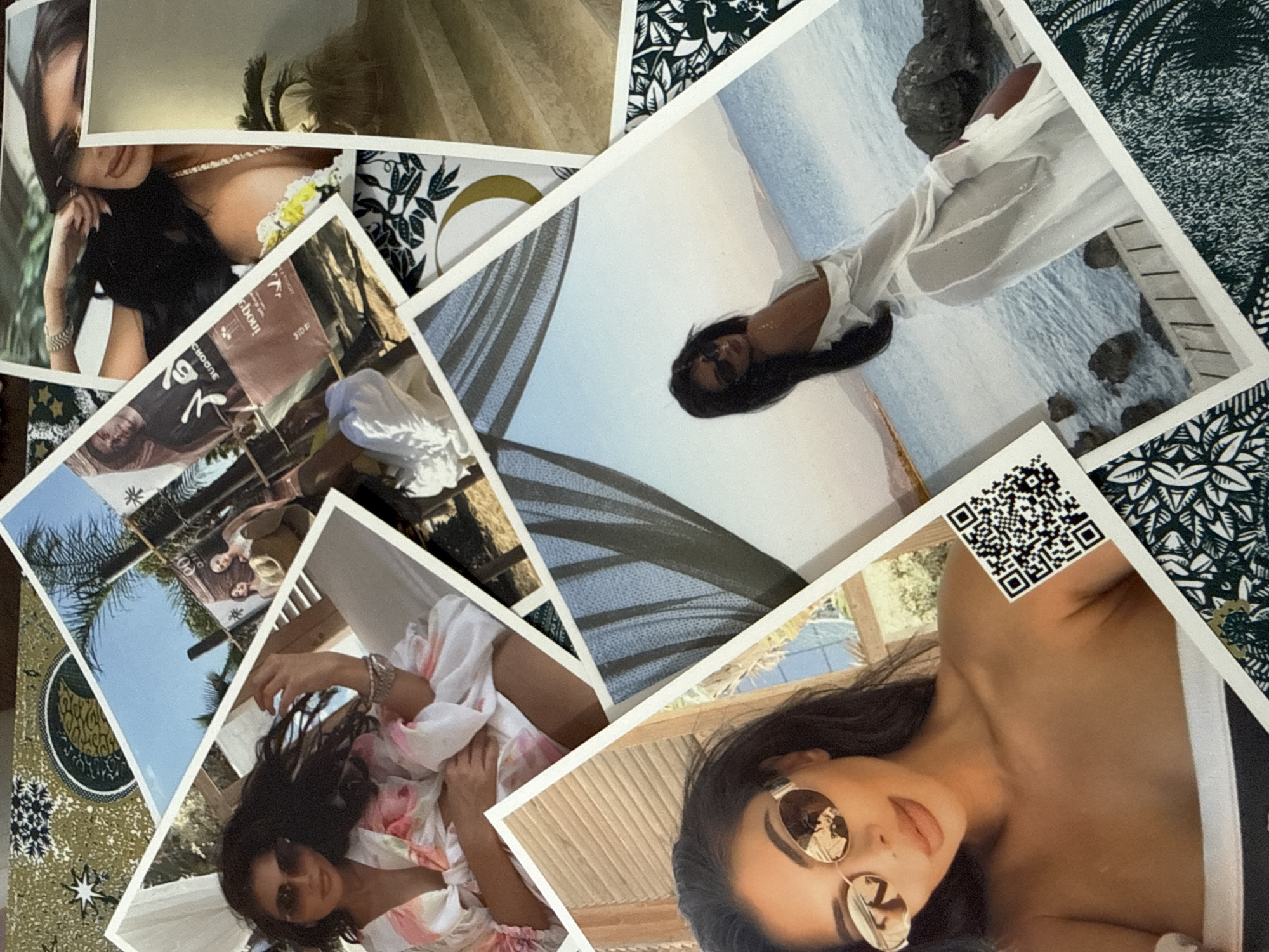 The image displays a collection of printed photographs scattered across a patterned surface. The photographs depict several individuals, primarily women, in various outdoor and poolside settings. One photograph shows a woman with dark hair and sunglasses, wearing a white and pink patterned garment, resting on a chaise lounge. Another features a woman in a sheer white dress standing by the sea, with dark hair and sunglasses. A third photograph captures two women and a man in the background, near palm trees and beach chairs. Other photos show close-ups of individuals' faces and torsos, some with jewelry and makeup. The patterned surface beneath the photos appears to be a fabric or tablecloth with a dark green and white leafy design, and some metallic gold accents. There is no discernible connection to the city of Plovdiv, Bulgaria, in the provided image.