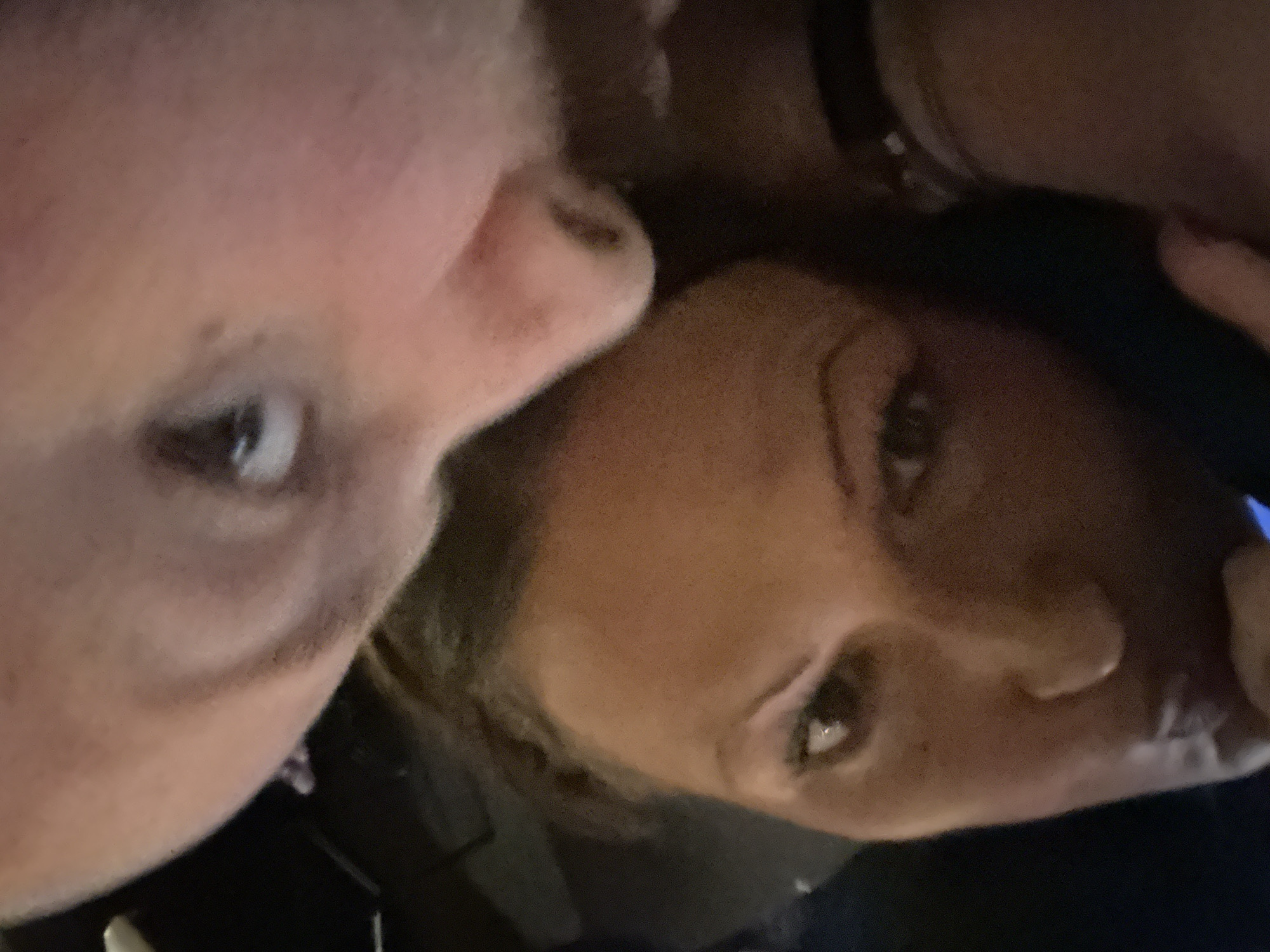 Close-up shot of two faces, one fair-skinned with a visible eye, the other with darker skin and both eyes visible. One is facing left and the other facing right. There is no identifiable London landmark present in the image. The location is undetermined.