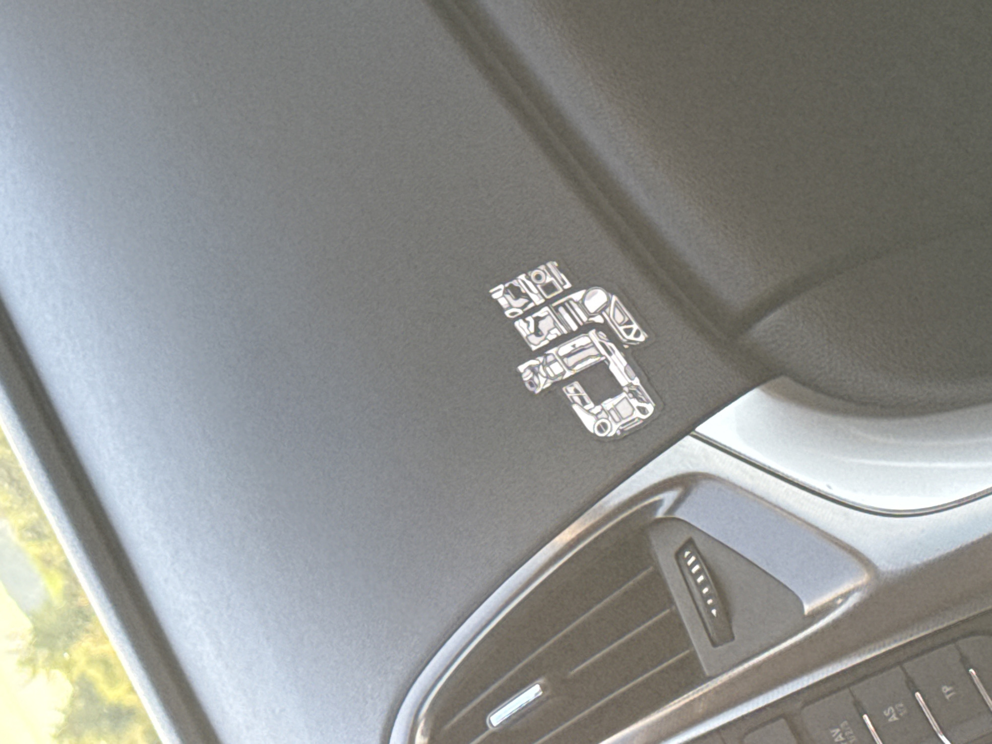 The image shows the interior of a car, specifically the dashboard area. A chrome-colored badge or emblem with a complex, abstract design is affixed to the dashboard surface. An air vent with adjustable slats is visible below the badge. Other parts of the car's interior, like the control panel, are also partially visible.
There is no information in the image that would connect it to the city of Slavyani, Bulgaria.