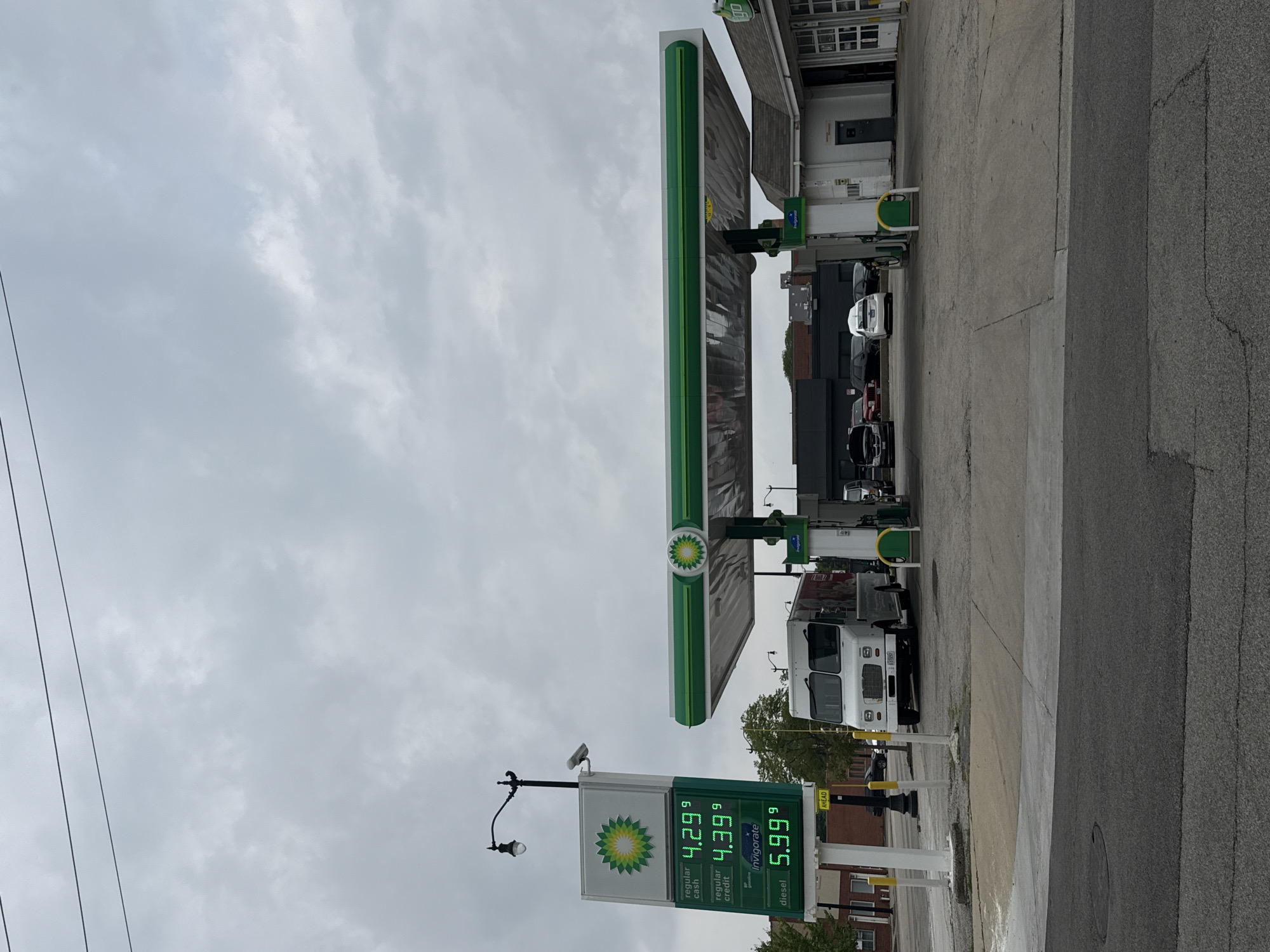 The image shows a BP gas station in Skokie, Illinois, United States of America, on a cloudy day. A gas price sign displays "regular cash $4.29", "regular credit $4.39", and "diesel $5.99". A white truck is parked under the gas station canopy. Several cars are also visible. The scene is viewed from a street level perspective.