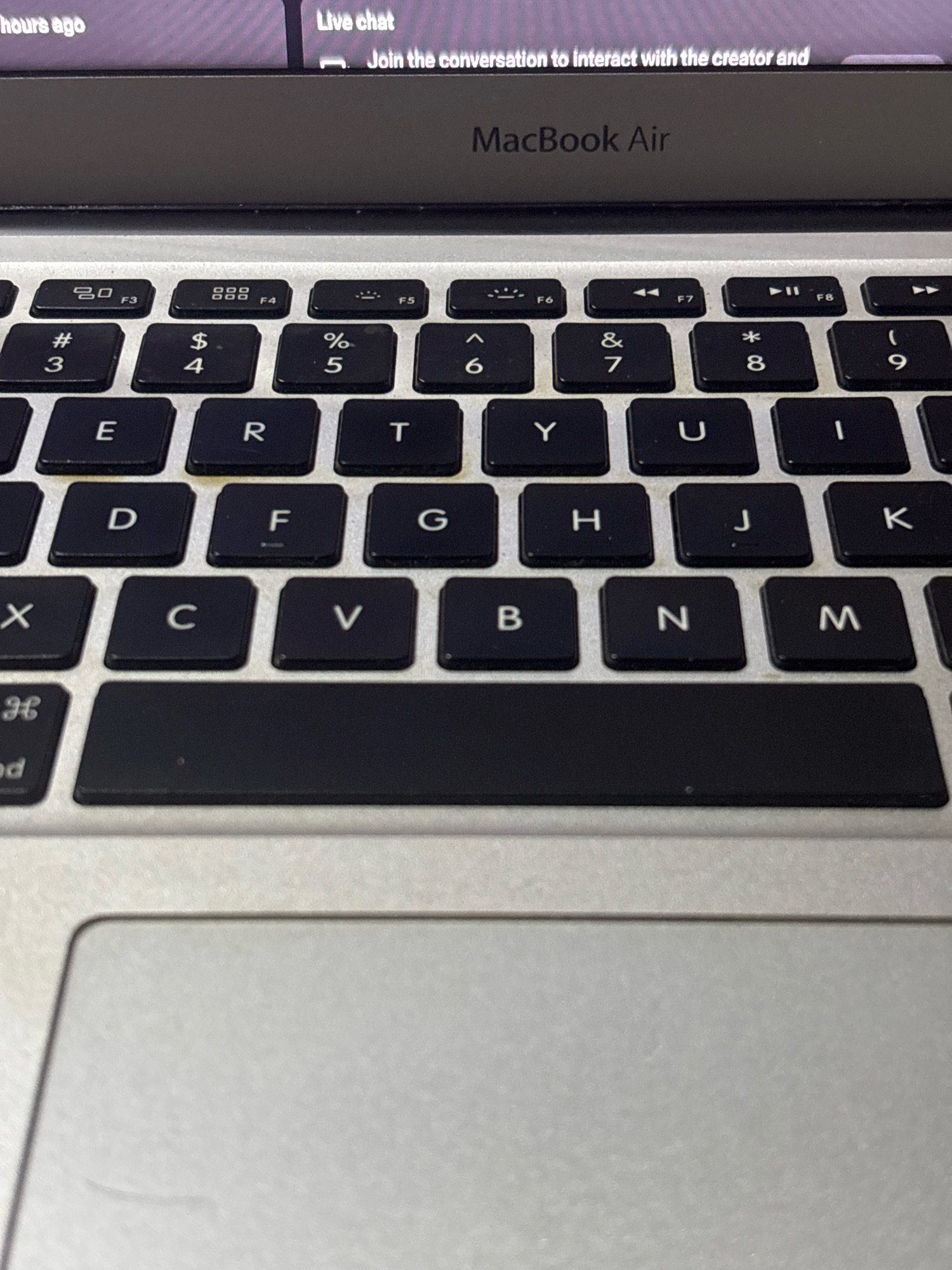 The image shows a close-up view of a MacBook Air keyboard and trackpad. The keys are black with white lettering, and the keyboard is part of a laptop. The screen of the laptop is visible at the top of the image, showing text that appears to be from a live chat interface. The laptop is silver, and the background is out of focus. There are no people visible in the image. The image does not contain any information about the city of Bekasi, Indonesia.