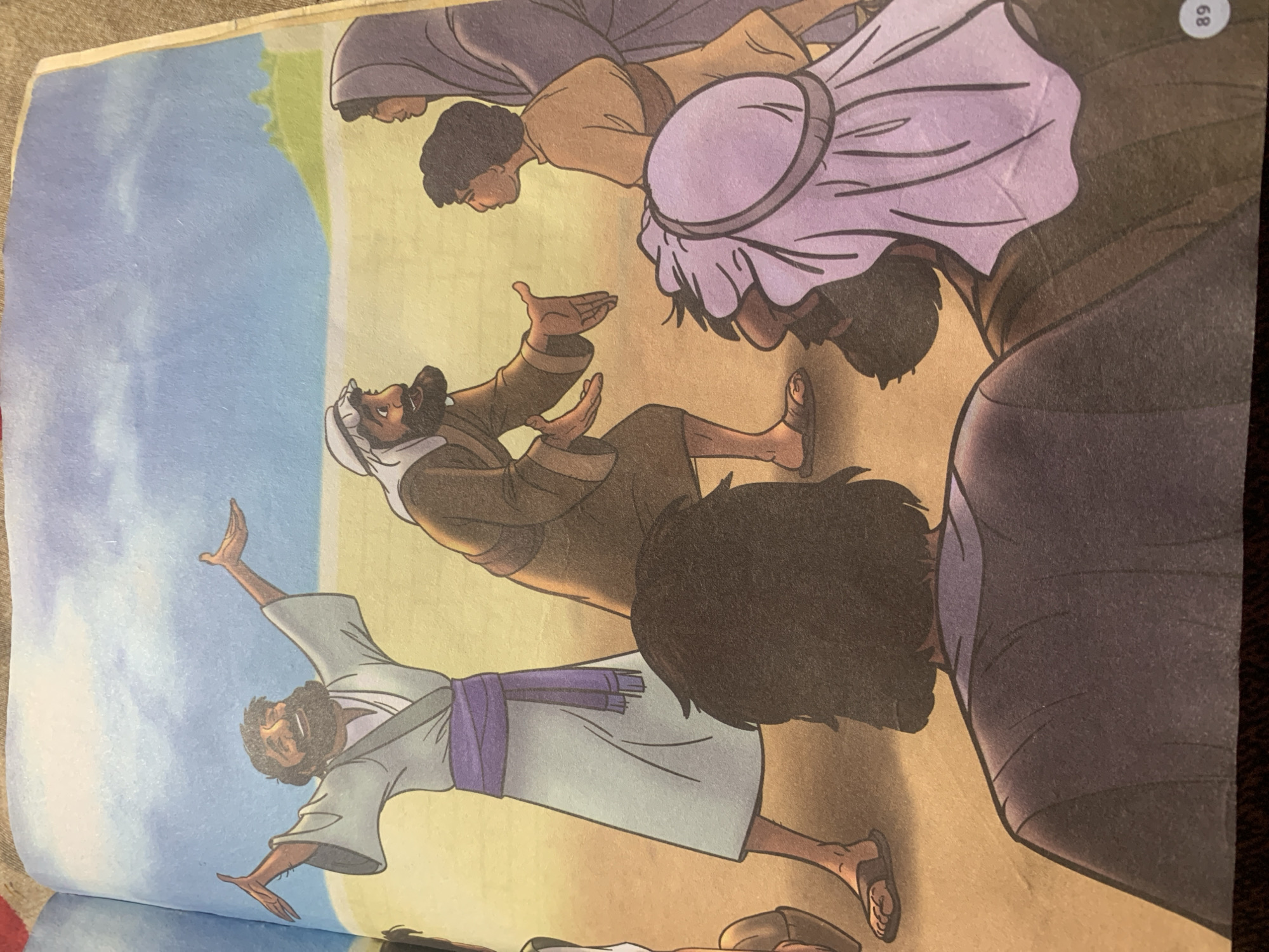 This is a colorful illustration depicting a religious or historical scene. In the foreground, the backs of several people are visible, suggesting they are observing an event. One person in the mid-ground, wearing a tan robe and a headscarf, is gesturing with outstretched hands, looking upwards with a joyous expression. Another man in a brown robe and headscarf is facing him, also with outstretched hands, appearing to be in conversation or explaining something. To the right, a young person in a tan tunic and an older person in a purple headscarf are observing the interaction. The background features a sandy or desert-like terrain with a faint green hill in the distance under a blue sky with scattered clouds. The image is a page from a book, with the number "89" visible in the bottom right corner. The location in the city of Jauro Yinu, Nigeria, is not depicted or indicated in this illustration.
