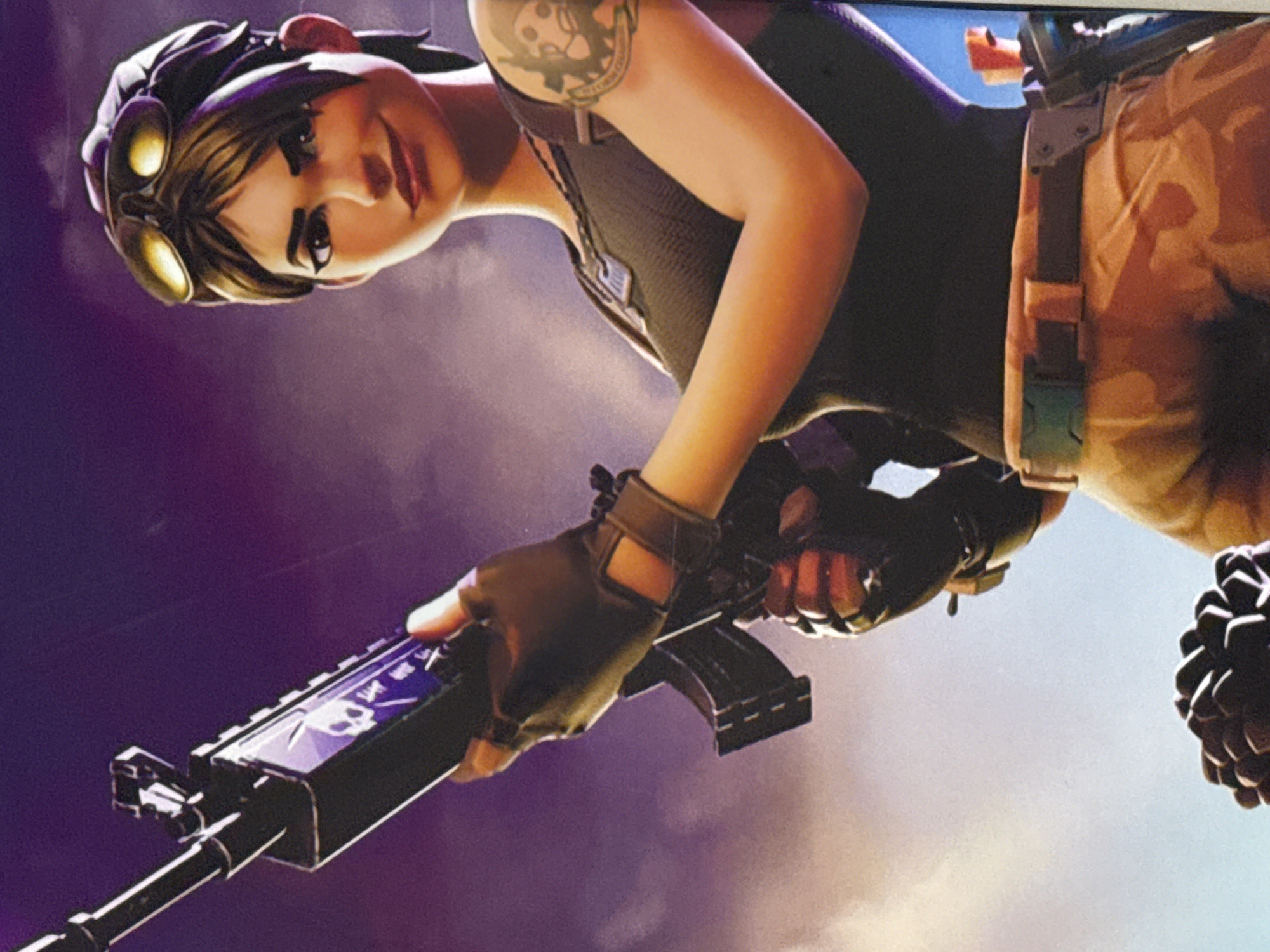 A woman is holding a rifle in a low-angle shot. She has brown hair and is wearing a hat with goggles on top. She has a dark tank top on and camouflage pants. She has a tattoo on her left arm. The background is a mix of purple and white. There is no visible evidence to suggest the location is Votkinsk, Russia.
