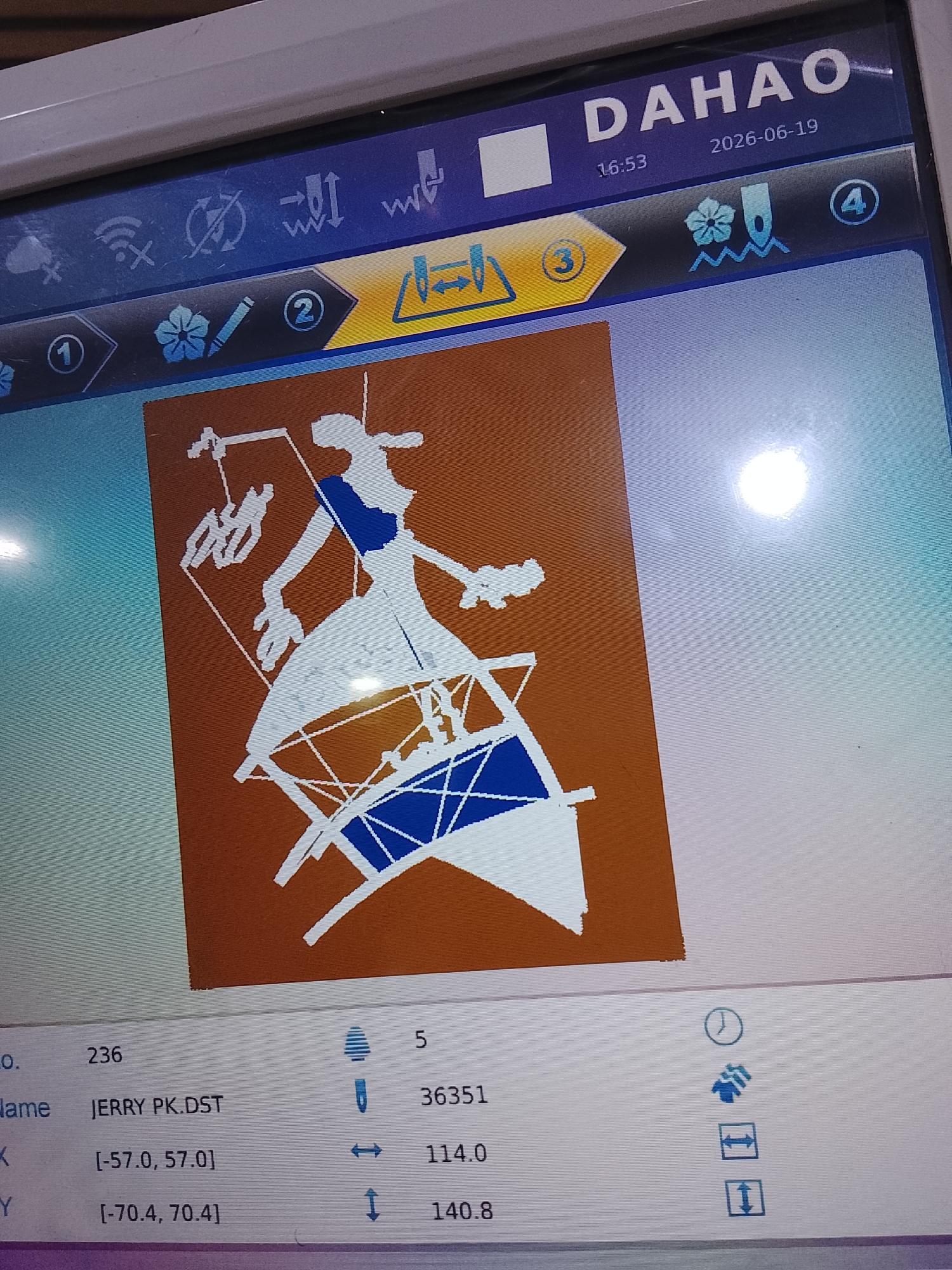 The image shows a close-up of a digital embroidery machine screen displaying a design. The design is a silhouette of a person, likely a woman, dancing or performing, dressed in a flowing gown with a sash. She is standing on a circular structure with radiating lines, possibly representing a stage or a prop. The design is rendered in white and blue against a solid brown background.
The screen also displays several interface elements. At the top, the brand name "DAHAO" is visible, along with a date "2026-06-19" and time "16:53". Below the design, there are data fields showing information such as "No. 236", "Name JERRY PK.DST", and coordinate values for X and Y axes. There are also icons and numerical values, including "5", "36351", "114.0", and "140.8". A progress bar or indicator is partially visible at the bottom. Several numbered icons (1, 2, 3, 4) suggest navigation or selection options within the machine's interface. The overall setting appears to be an indoor environment, likely a workshop or production facility where embroidery machines are operated. The lighting on the screen suggests it is likely daytime, as indicated by the bright reflection on the screen. No specific cues about the location in Rumuepirikom, Nigeria are visible on the screen itself, but the prompt provides this context.