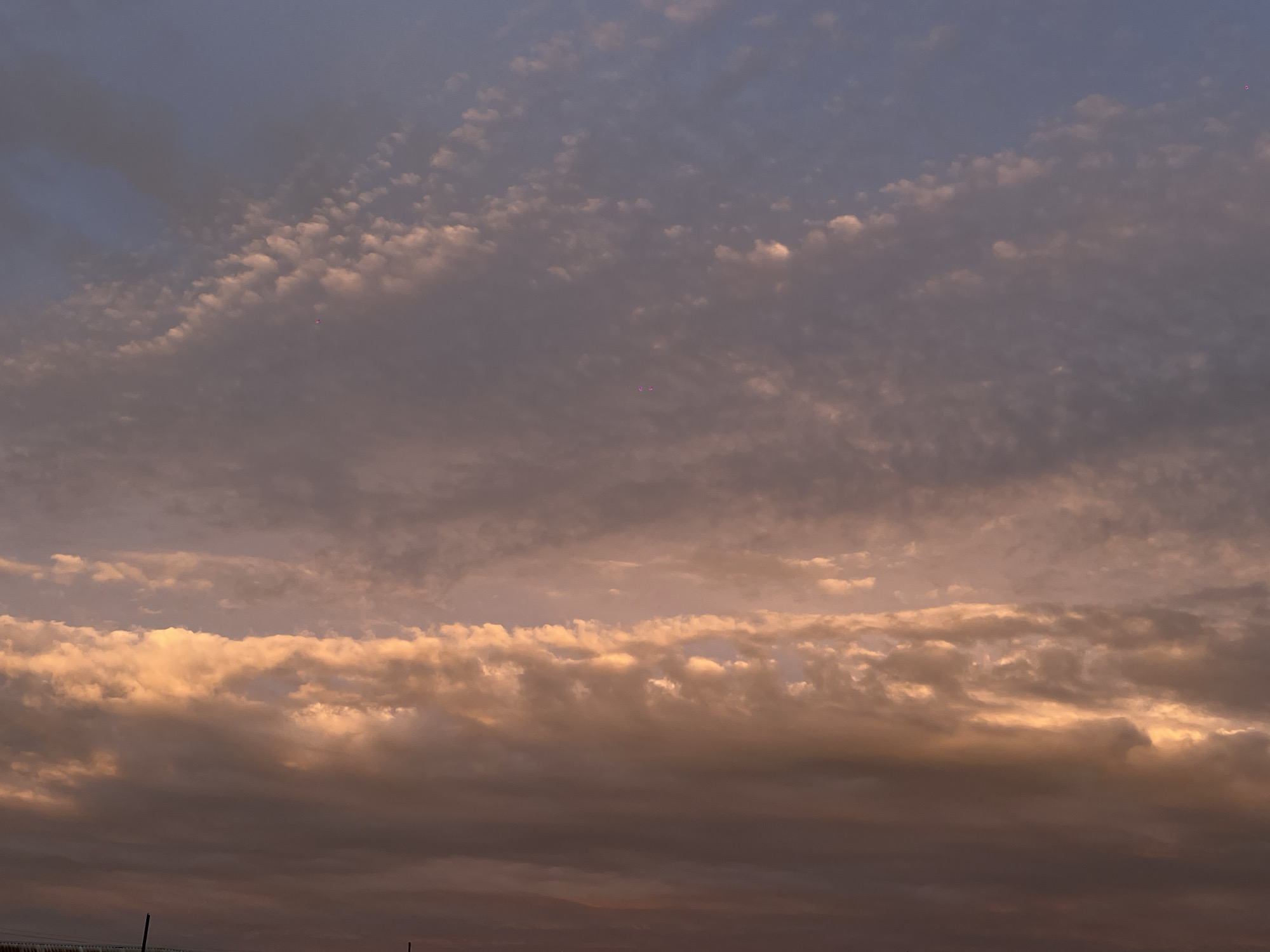 The image depicts a cloudy sky with varying shades of gray and hints of golden light. There is no discernible indication of the city of Novopokrovskaya, Russia, or any other specific location. The scene is limited to the sky.