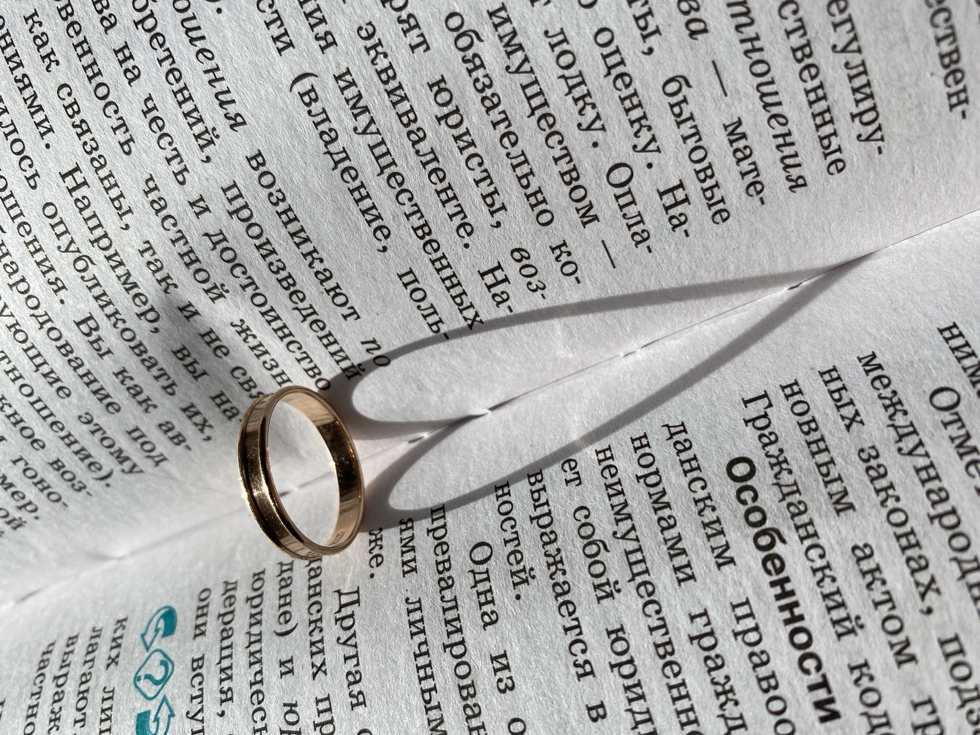 A gold ring casts a heart-shaped shadow on a page of text printed in Russian. The text appears to be from a legal document, potentially pertaining to civil law or property rights.